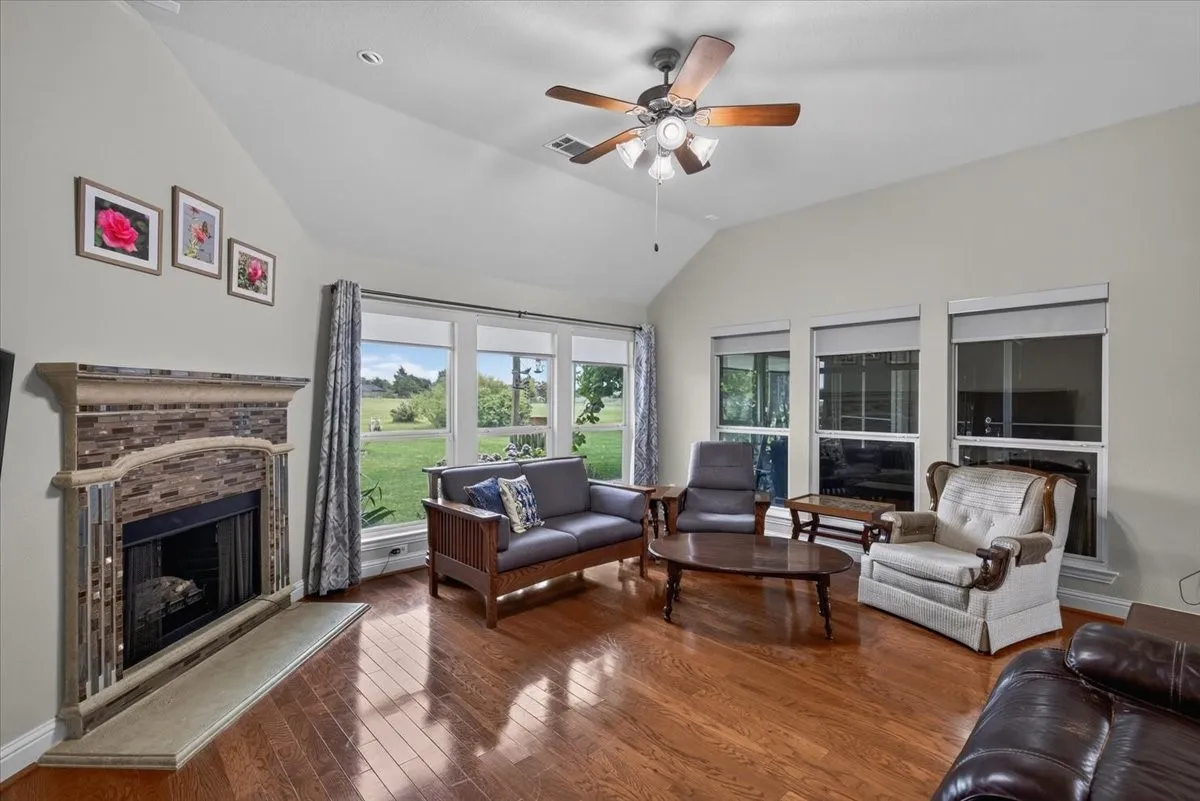 Living room with wood flooring, a fireplace and lots of windows for natural light.
