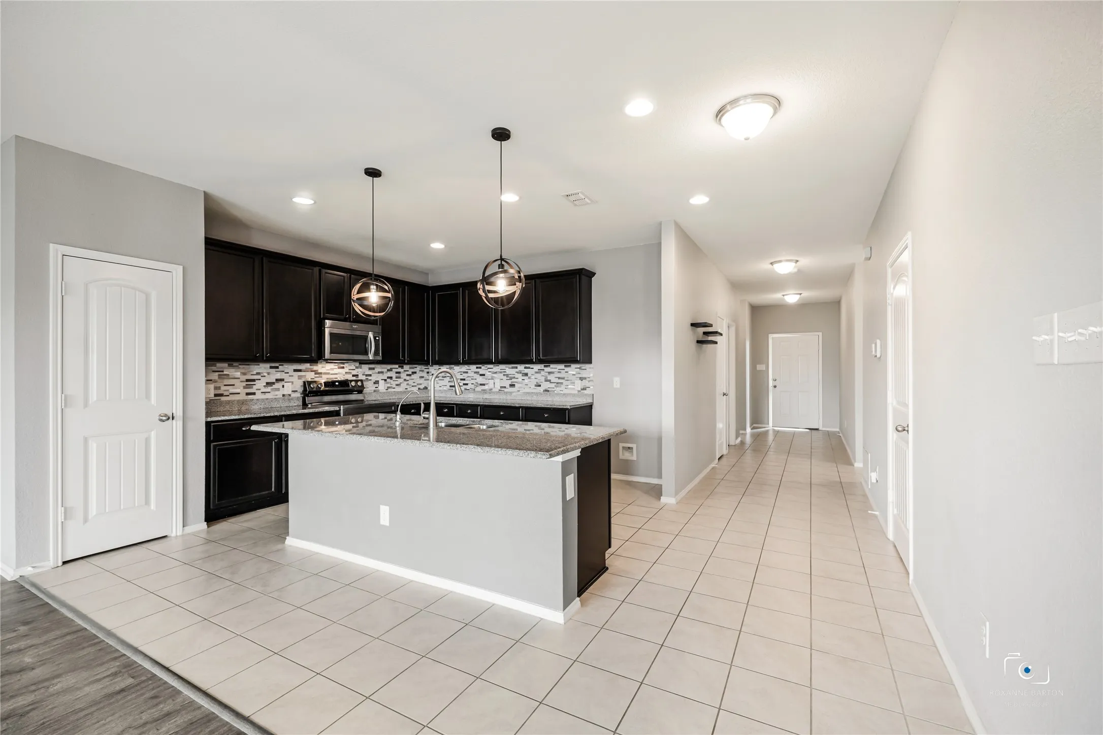 Large Kitchen Island with sink, breakfast bar, Designer pendants, and granite counters