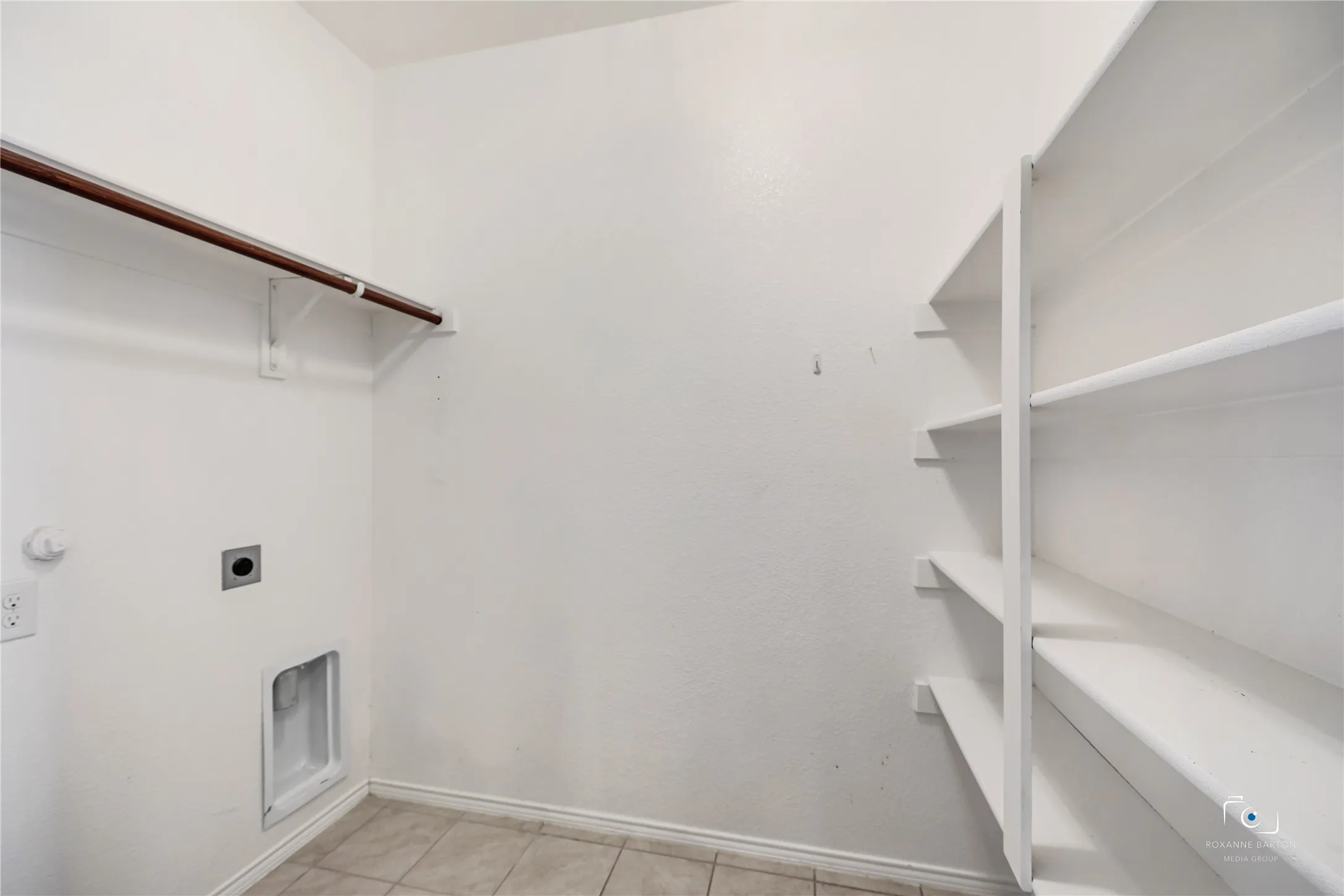 This large laundry room features hanging clothes rods and a wall of shelving for home storage items. Maybe a second pantry as it is across from the kitchen.
