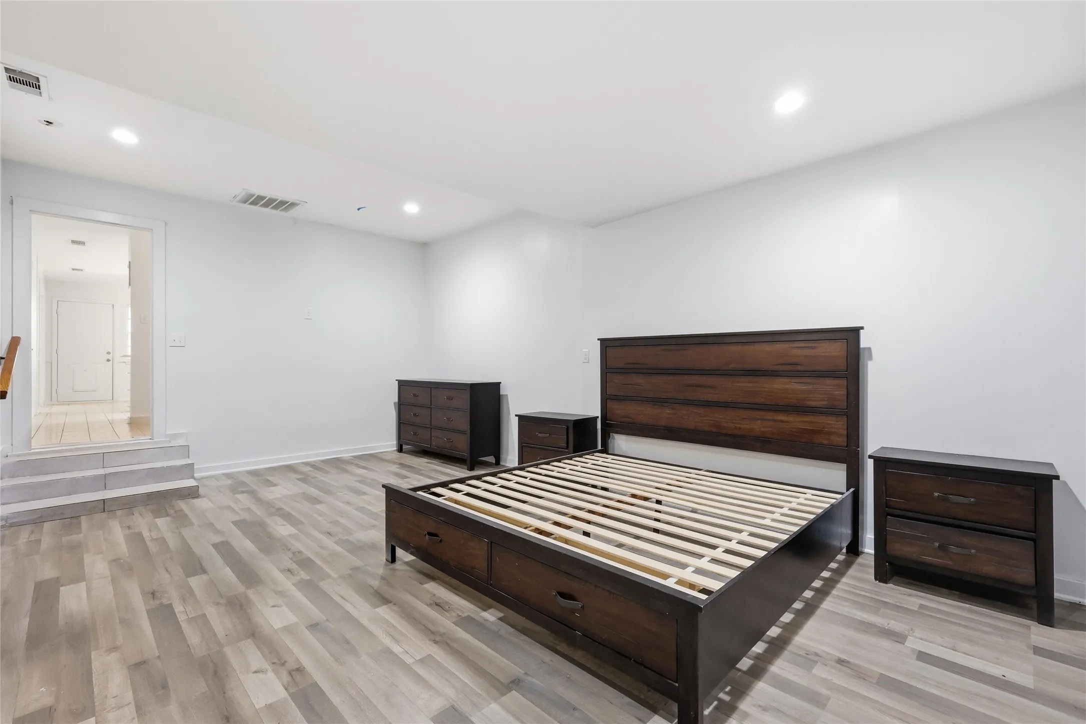 Spacious room featuring light-toned wood-finish flooring and recessed lighting