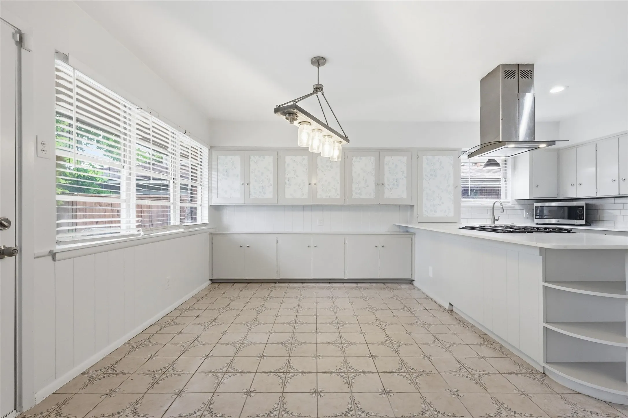 Kitchen with white cabinetry, tile flooring, and a large central island