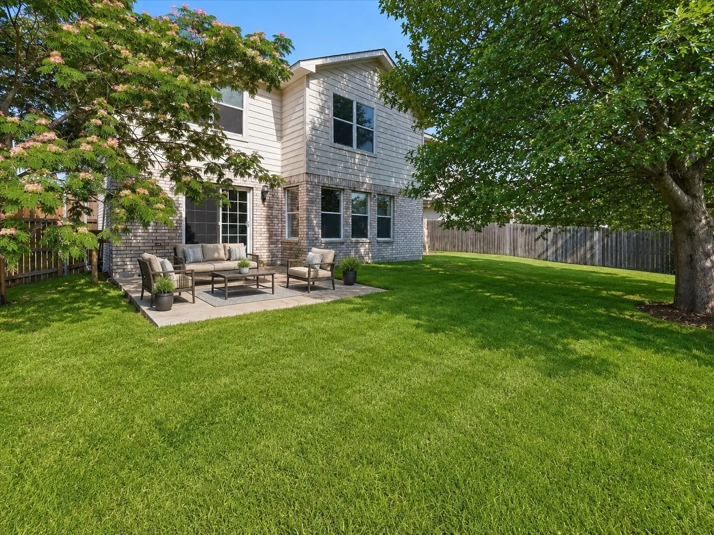 Expansive backyard featuring a concrete patio, a sliding glass door, and full brick and siding exterior