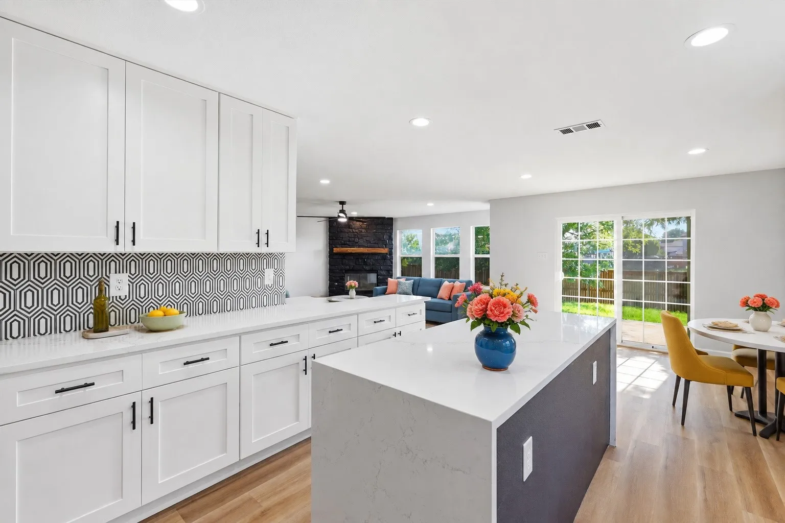White shaker cabinetry, patterned tile backsplash, light-toned wood-finish flooring, sliding glass door, and recessed lighting