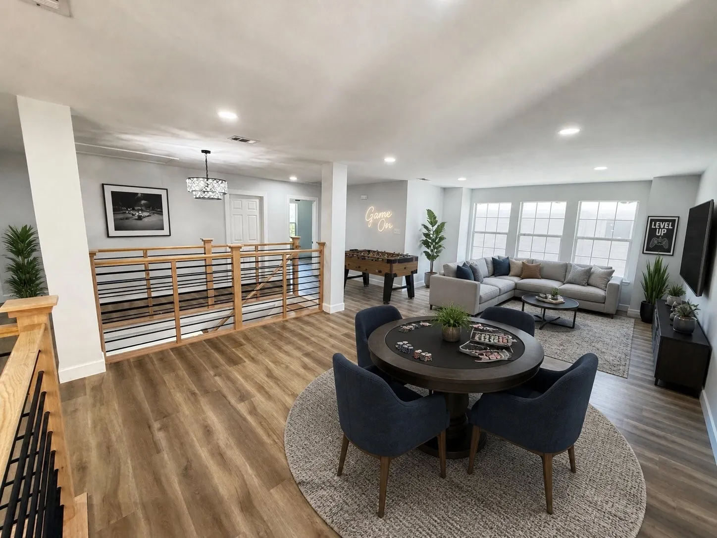 VIRTUALLY STAGED Open-concept recreation area featuring wood-finish flooring, a contemporary wood and metal railing system, recessed lighting, and multiple windows