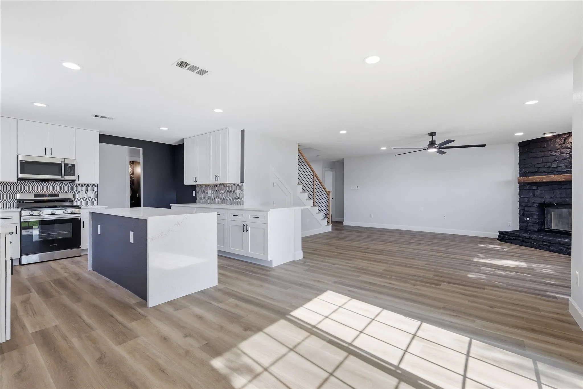 Open-concept interior featuring light wood-finish flooring, recessed lighting, and a modern kitchen