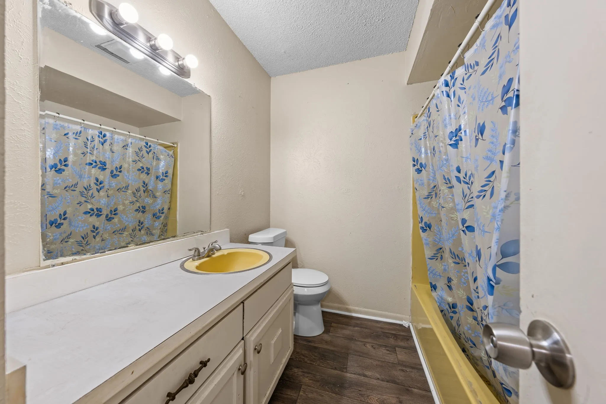 Full bath featuring dark wood-style floors, vanity, a textured ceiling, and shower / tub combo