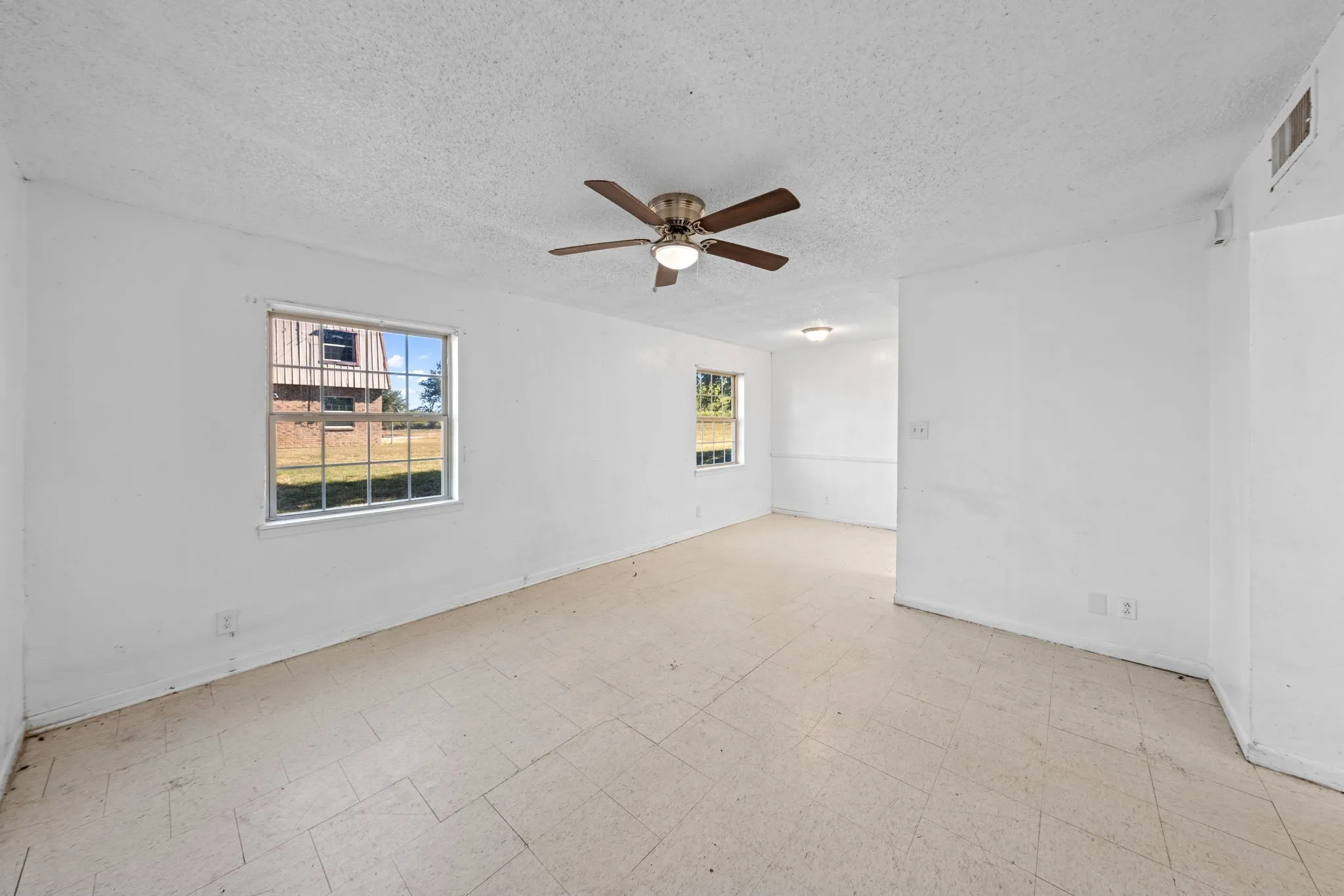 Spare room featuring light flooring, a textured ceiling, and ceiling fan