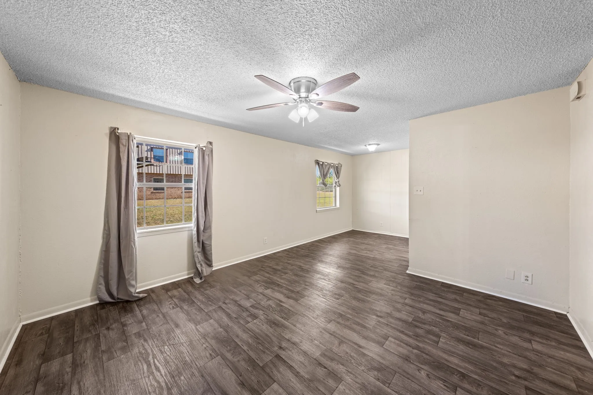 Empty room with dark wood-type flooring, ceiling fan, and a textured ceiling