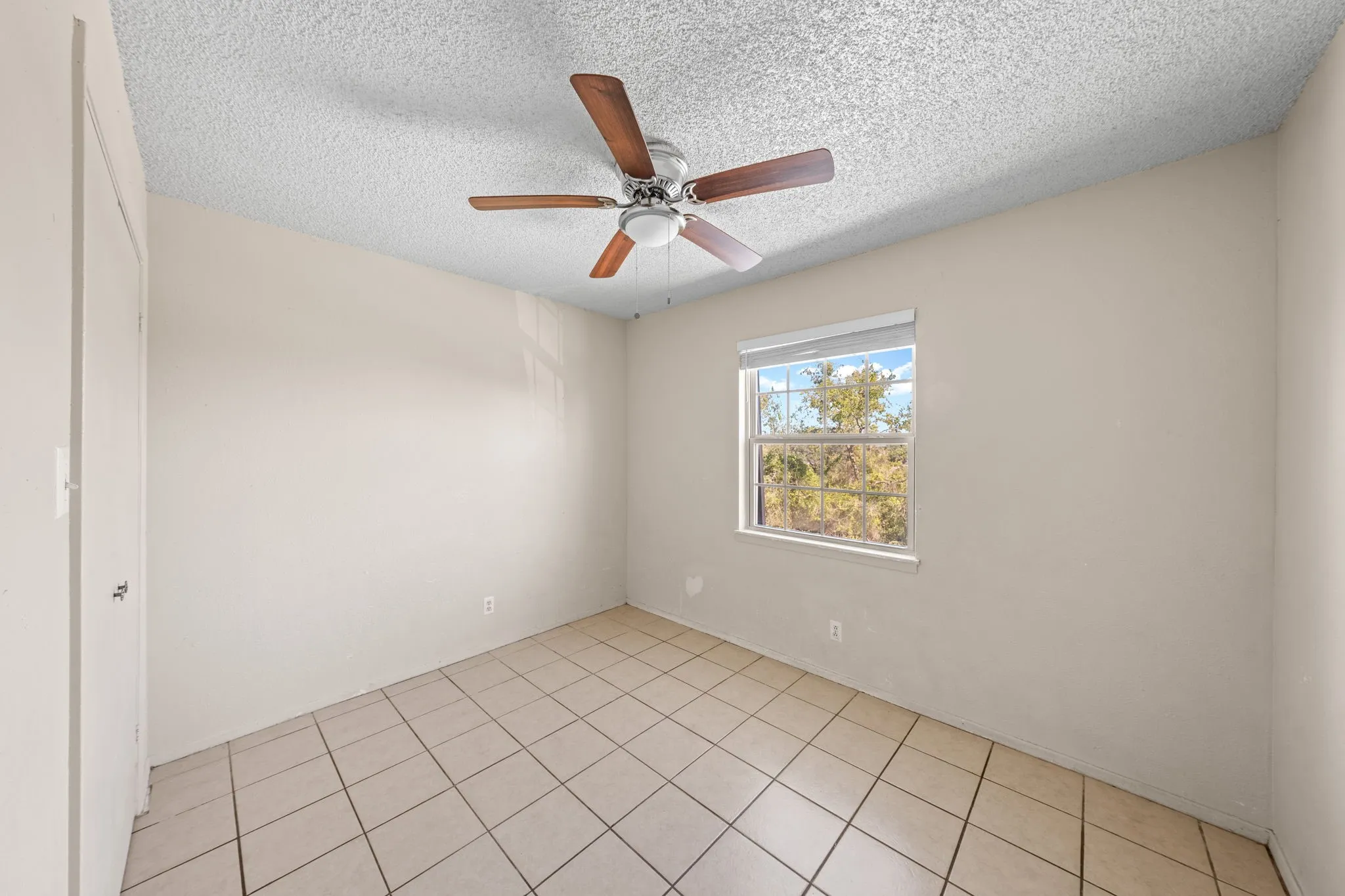 Spare room featuring a textured ceiling, ceiling fan, and light tile patterned floors