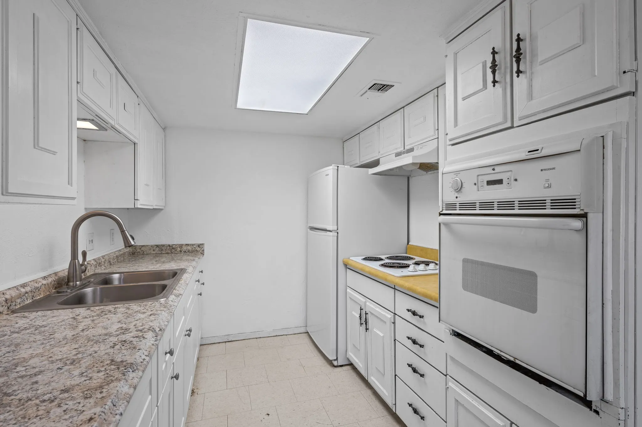 Kitchen with white cabinets, white appliances, light countertops, and under cabinet range hood