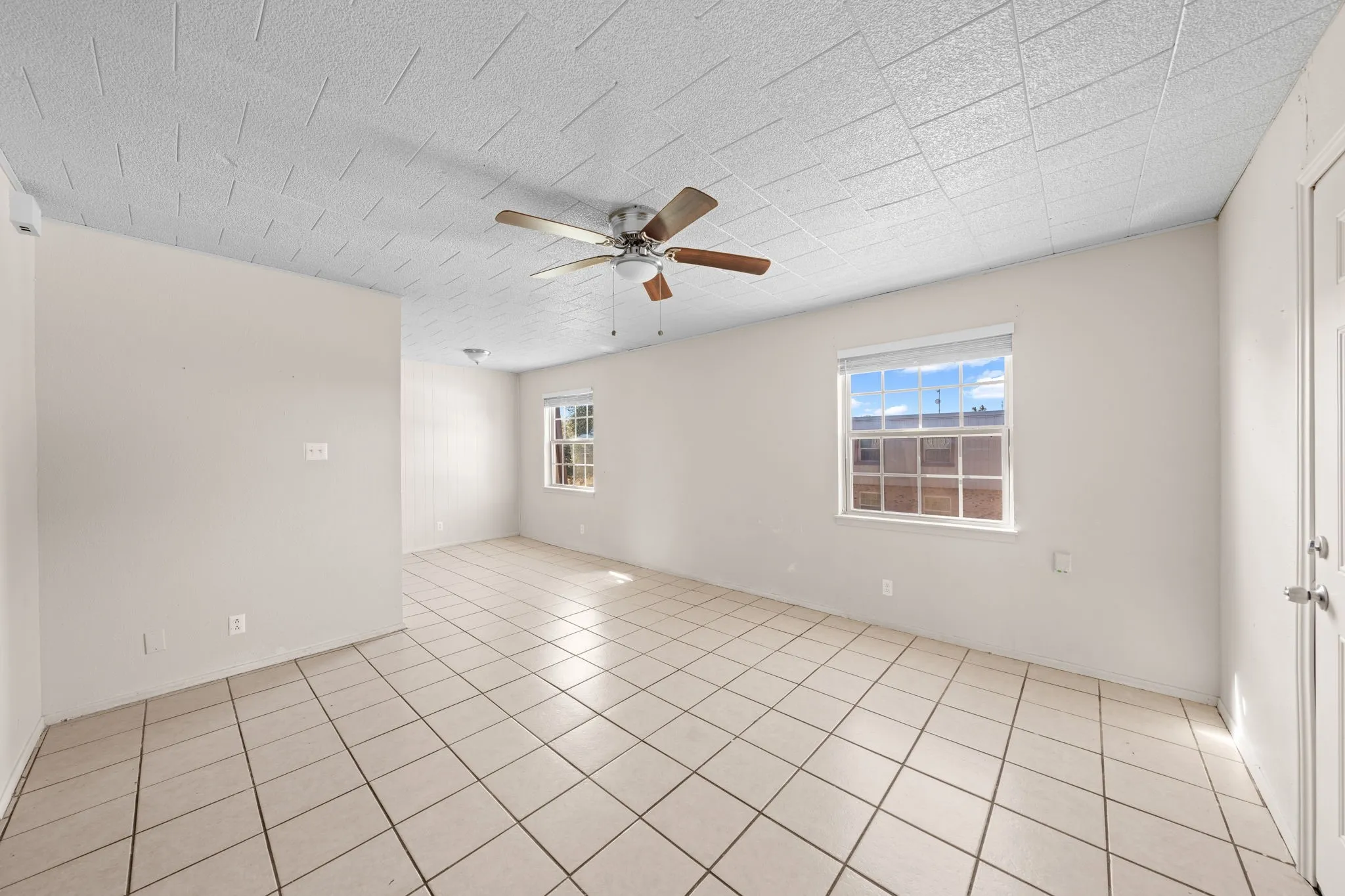 Empty room featuring ceiling fan and light tile patterned floors