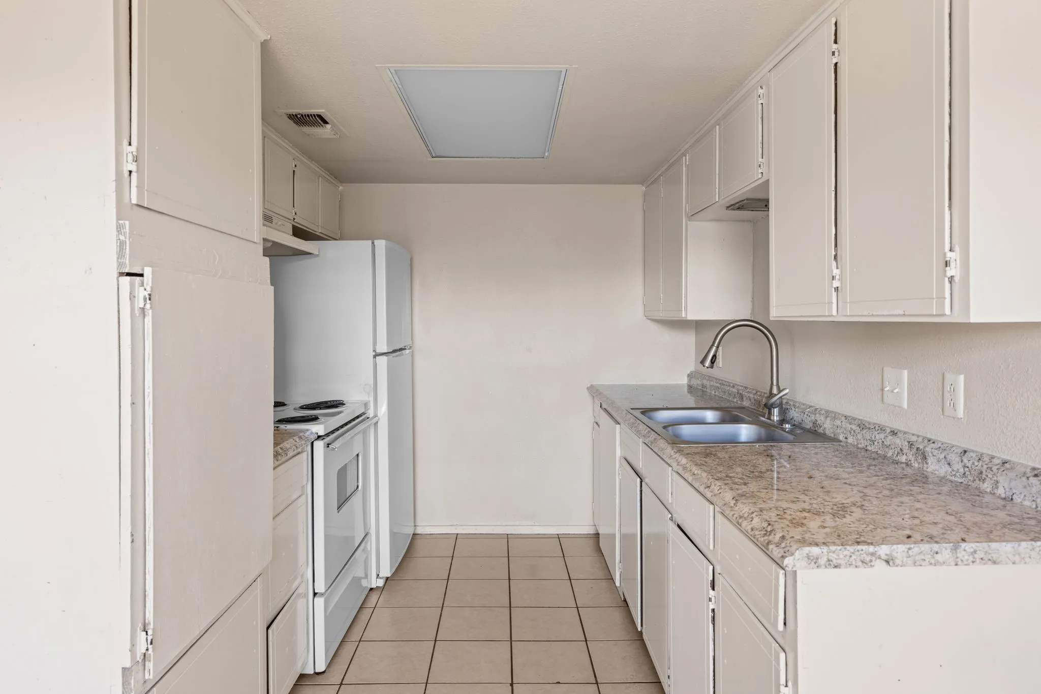 Kitchen with light countertops, white range with electric cooktop, light tile patterned floors, and white cabinetry
