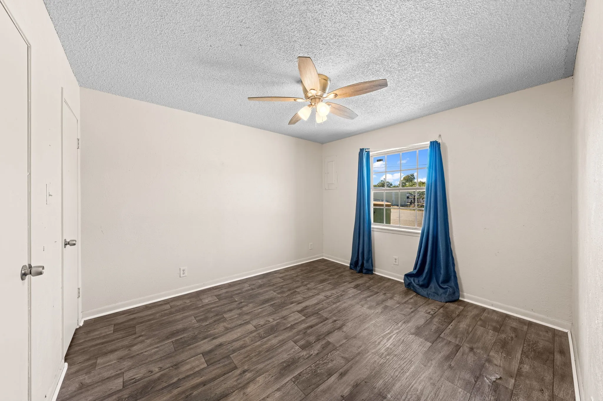 Spare room with dark wood finished floors, ceiling fan, and a textured ceiling