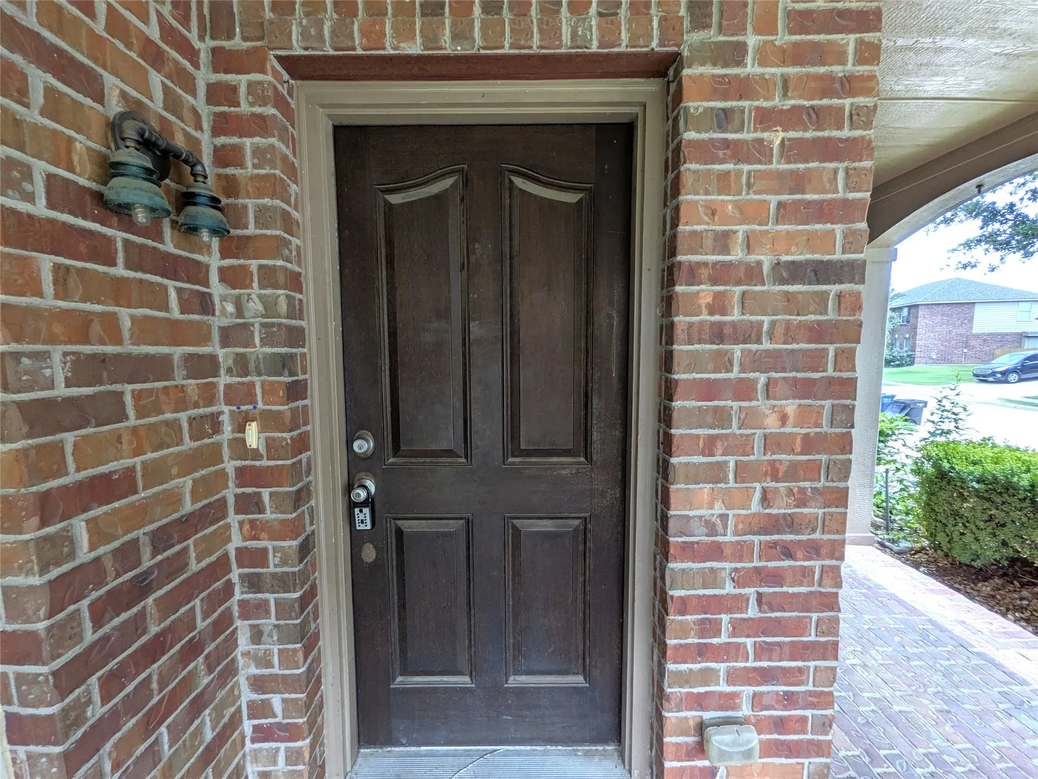Solid wood entry door with paneling, sidelight, and an exterior wall lantern