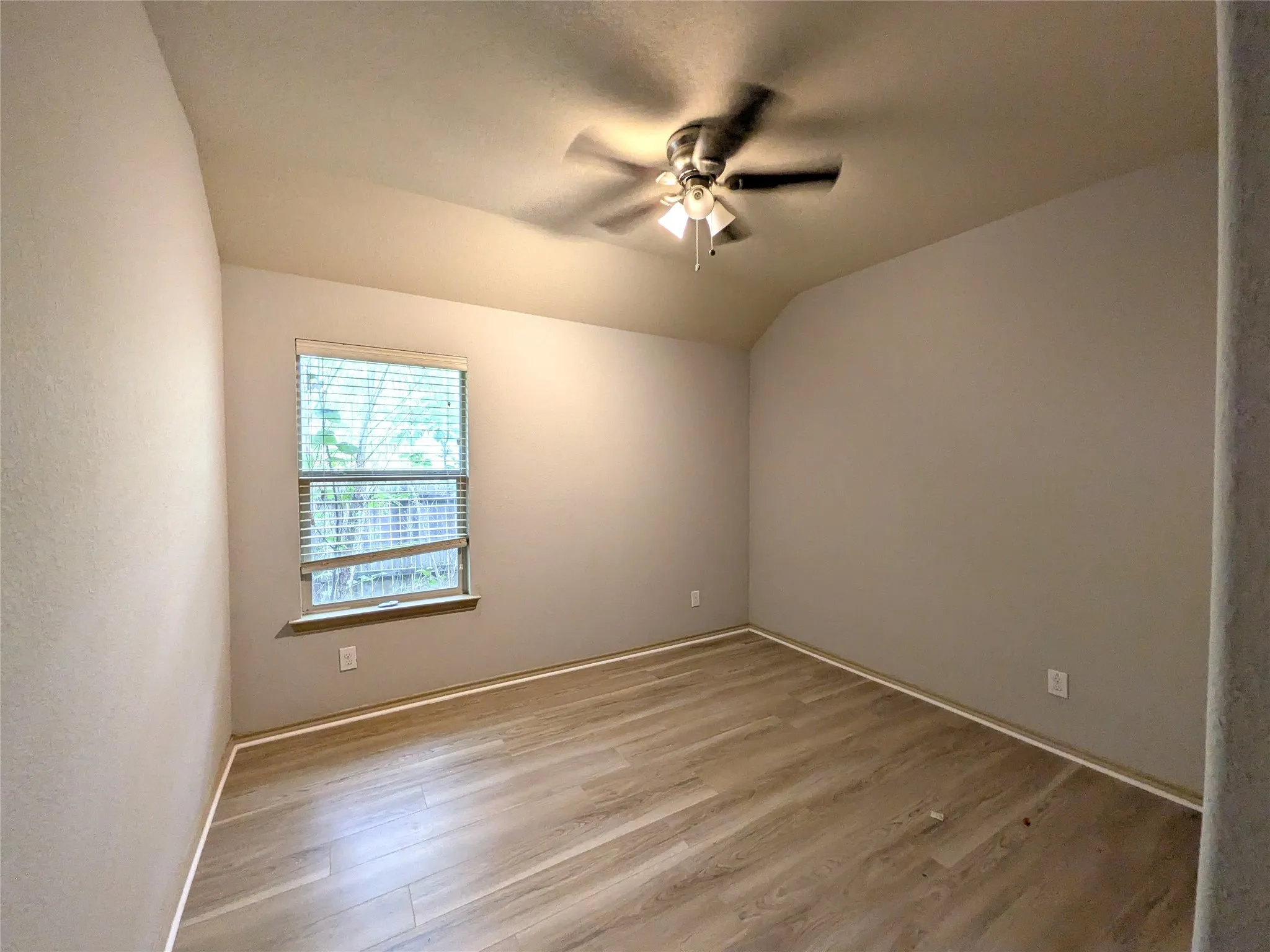 Room featuring wood-finish flooring, neutral wall paint, and a window with blinds