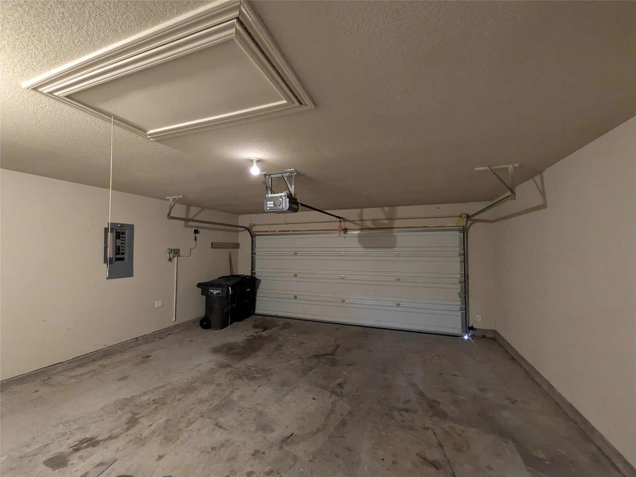 Attached single-car garage featuring an automatic overhead door opener, a finished ceiling with an access panel, and painted walls