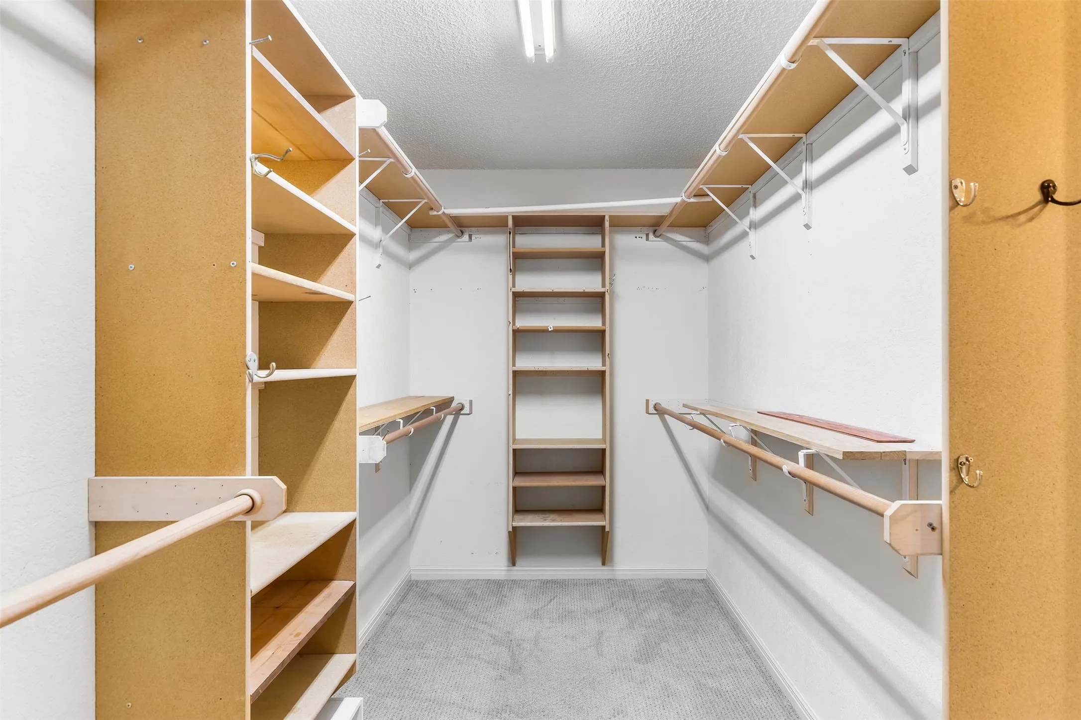 Built-in shelving, multiple hanging rods, and soft carpet flooring