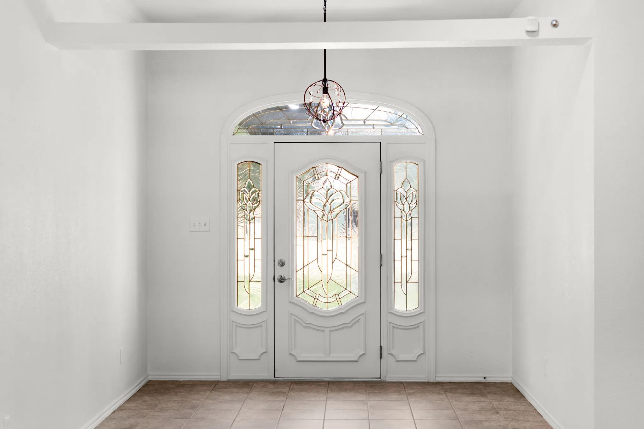 Entryway featuring a decorative front door with leaded glass panels, arched transom window, and sidelights