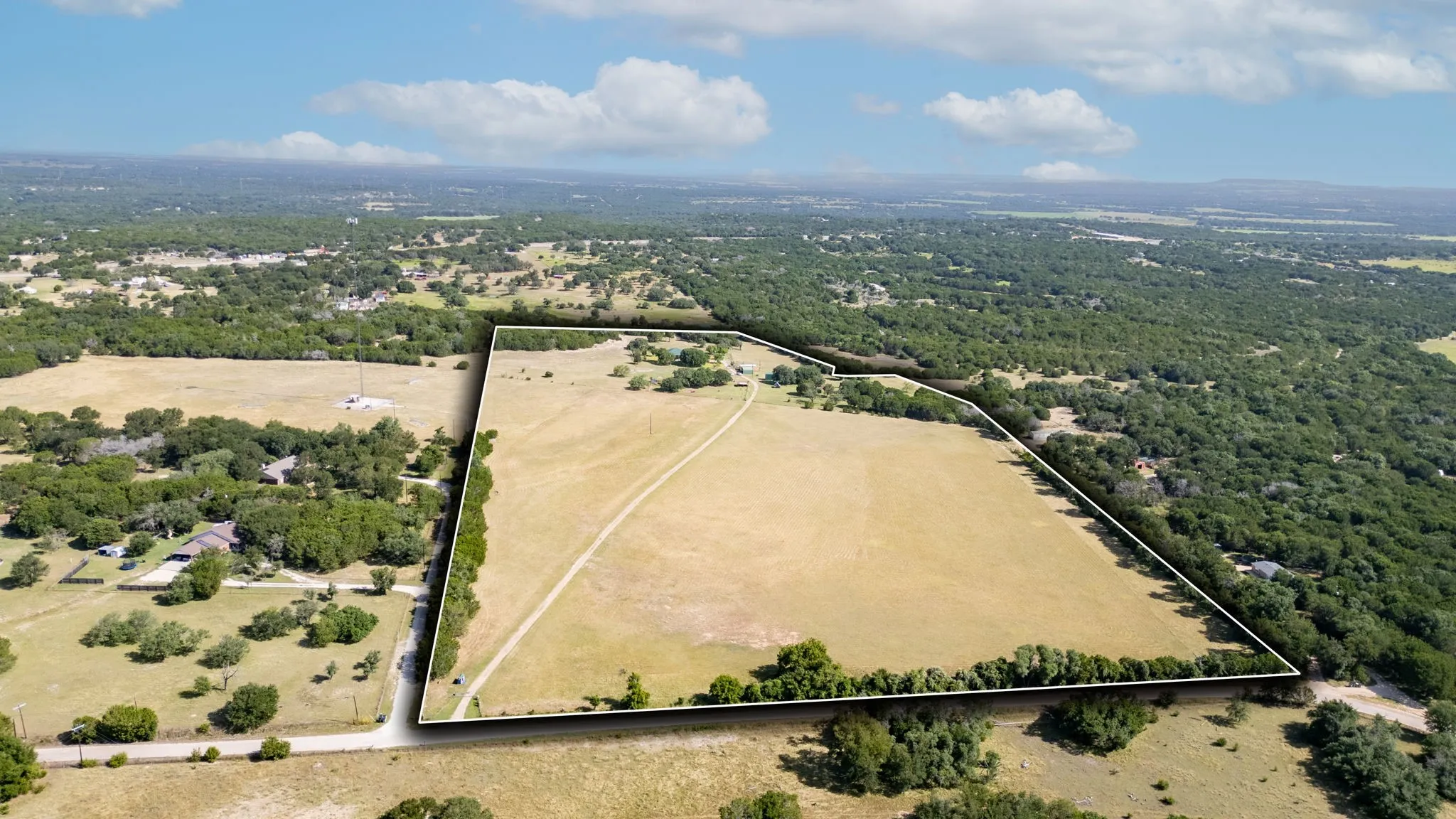 Expansive parcel featuring open fields and mature tree lines, with a defined property boundary