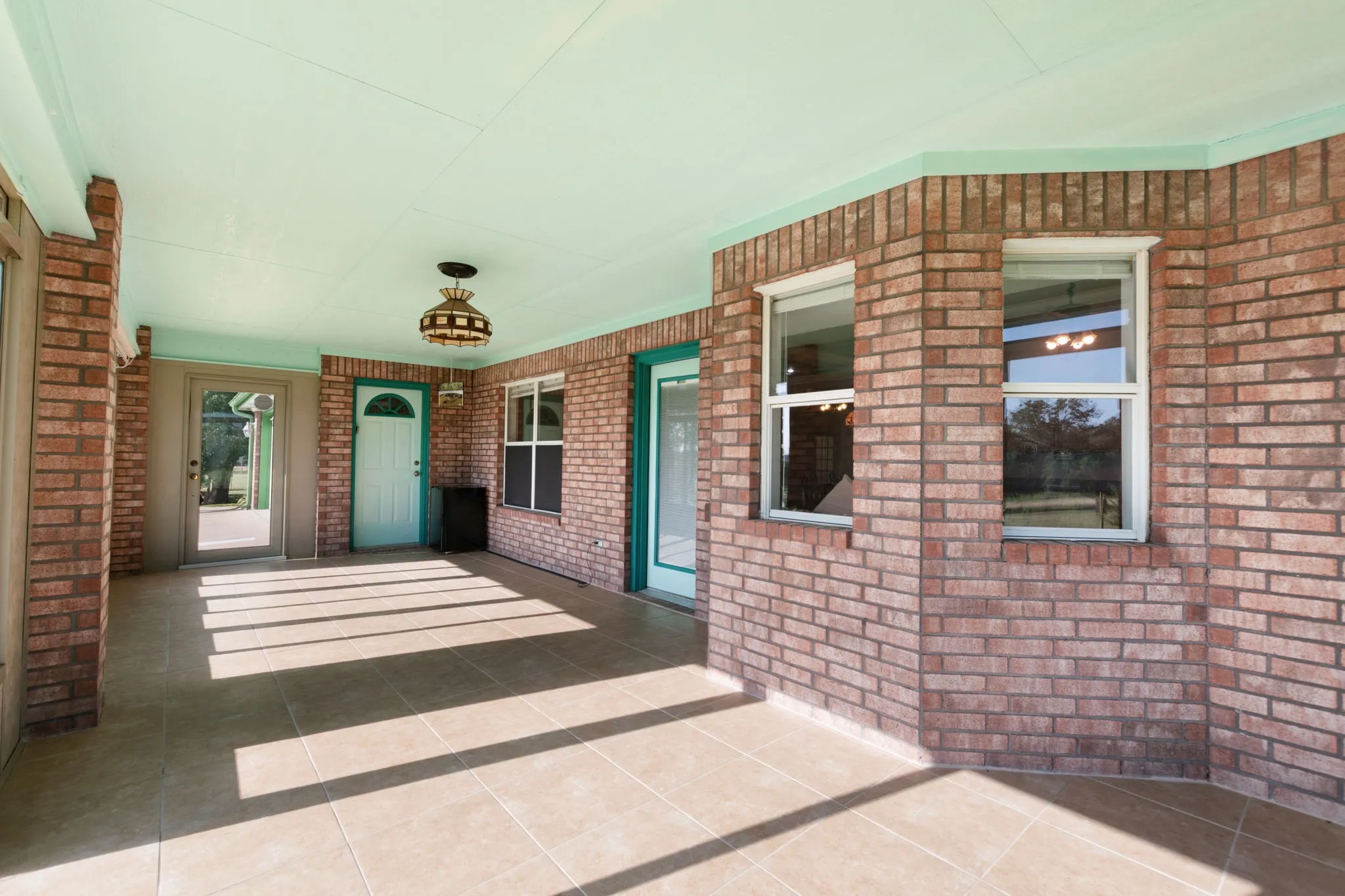 Covered patio featuring brick exterior walls and tile flooring