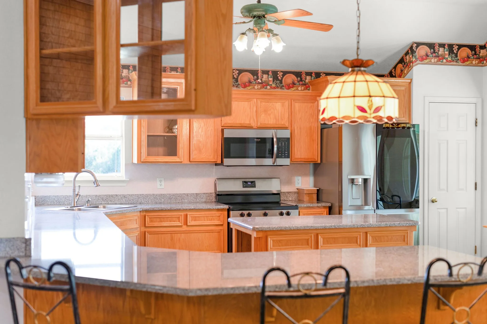 Kitchen featuring wood cabinetry, stainless steel appliances, a center island with bar seating, and granite-finish countertops