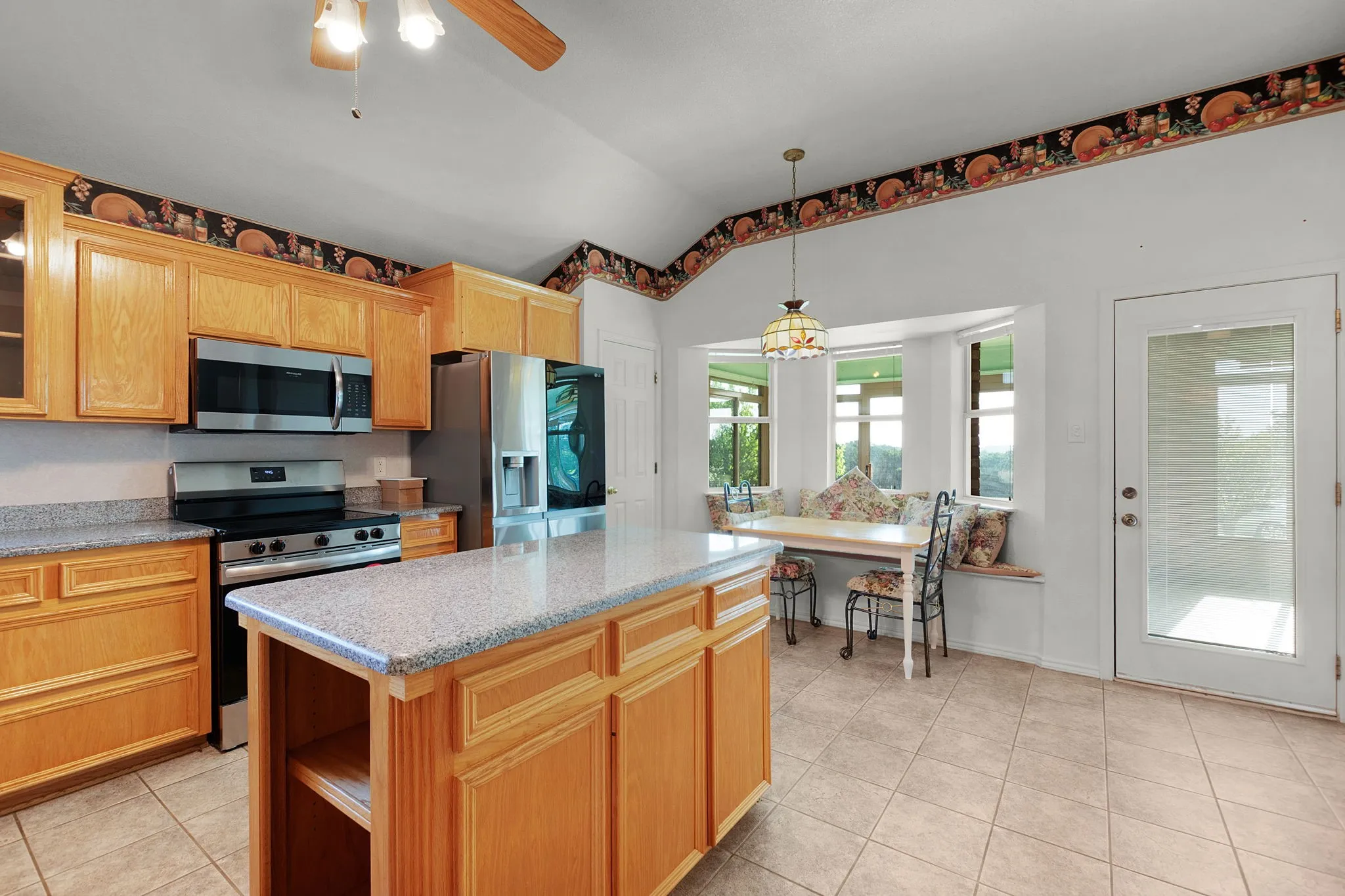 Kitchen featuring light wood cabinetry, stainless steel appliances, a center island with a light-toned countertop, and tile flooring