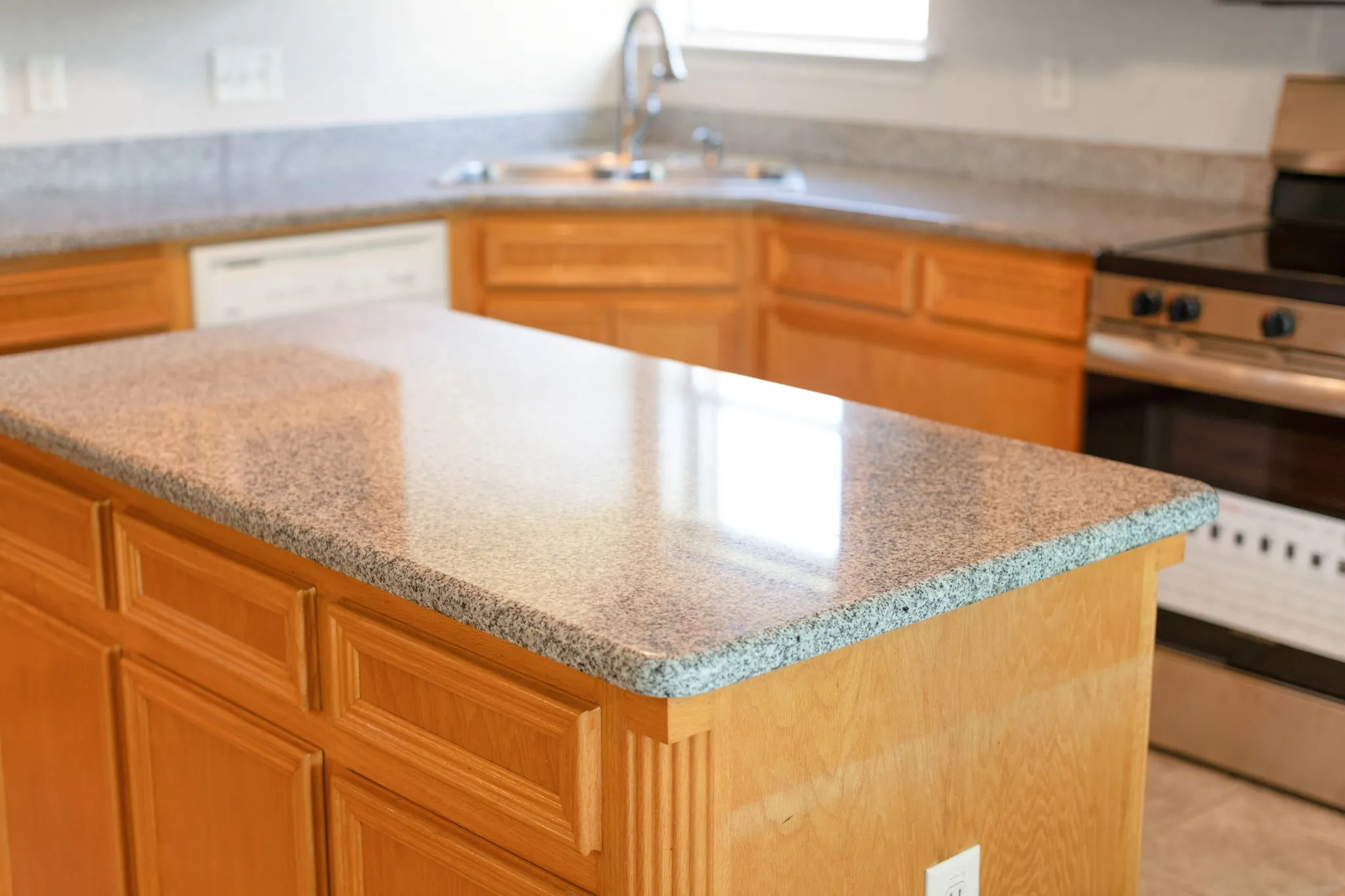 Kitchen island featuring a speckled countertop and light wood-finish cabinetry