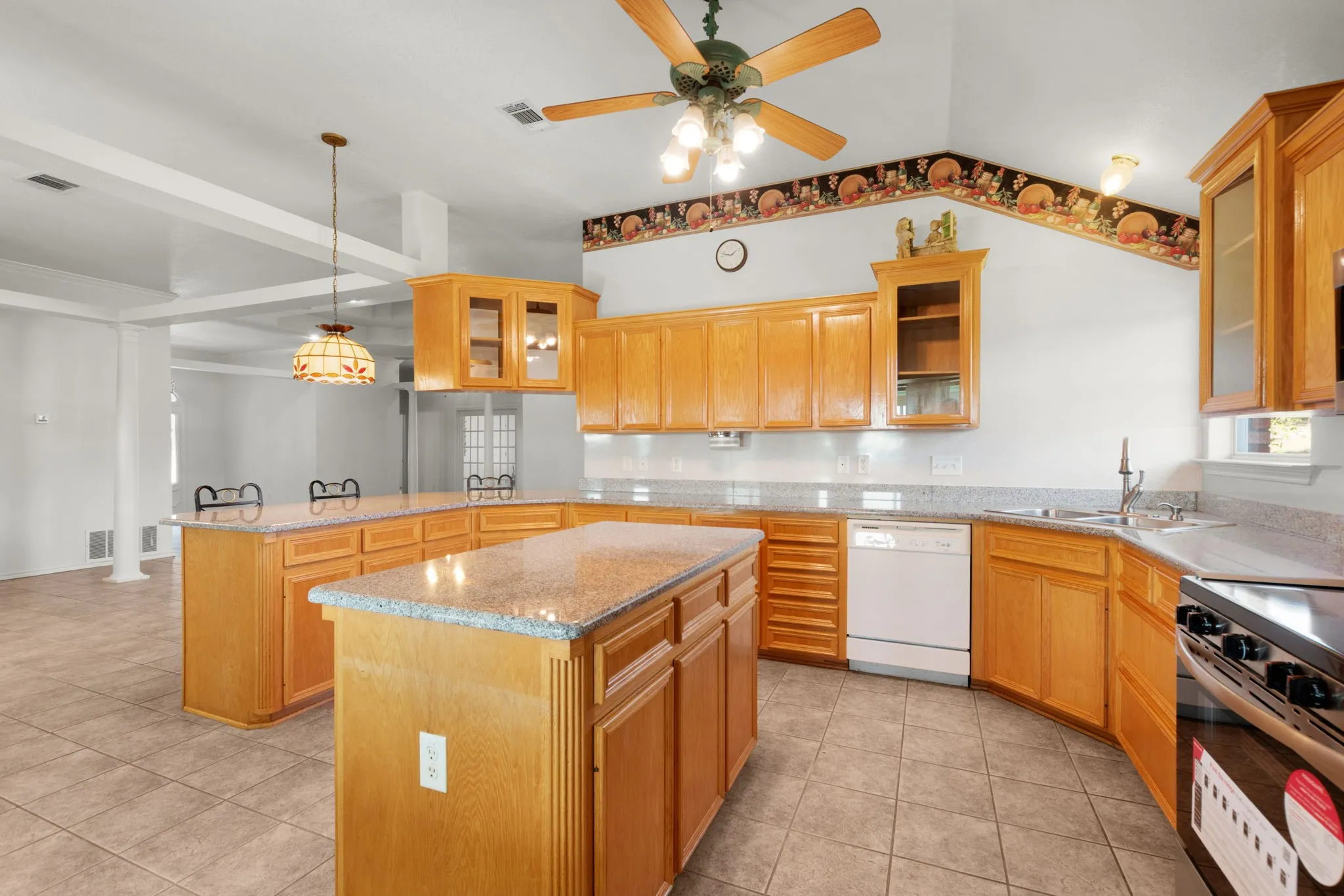Kitchen featuring a large island, wood cabinetry, granite countertops, tile flooring, and a ceiling fan