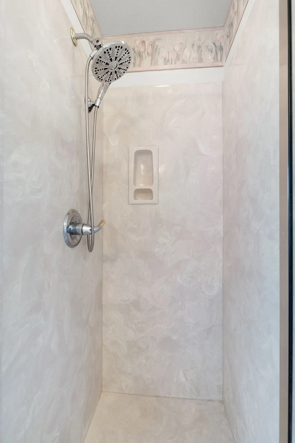 Shower enclosure featuring light-toned, swirled wall panels