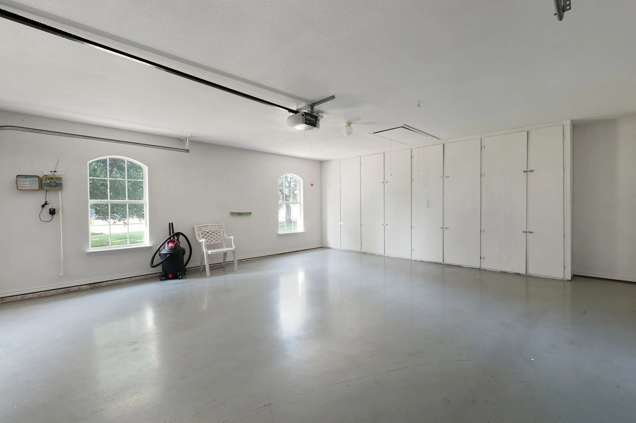 Spacious garage featuring a light gray concrete floor, white walls, and built-in storage cabinetry
