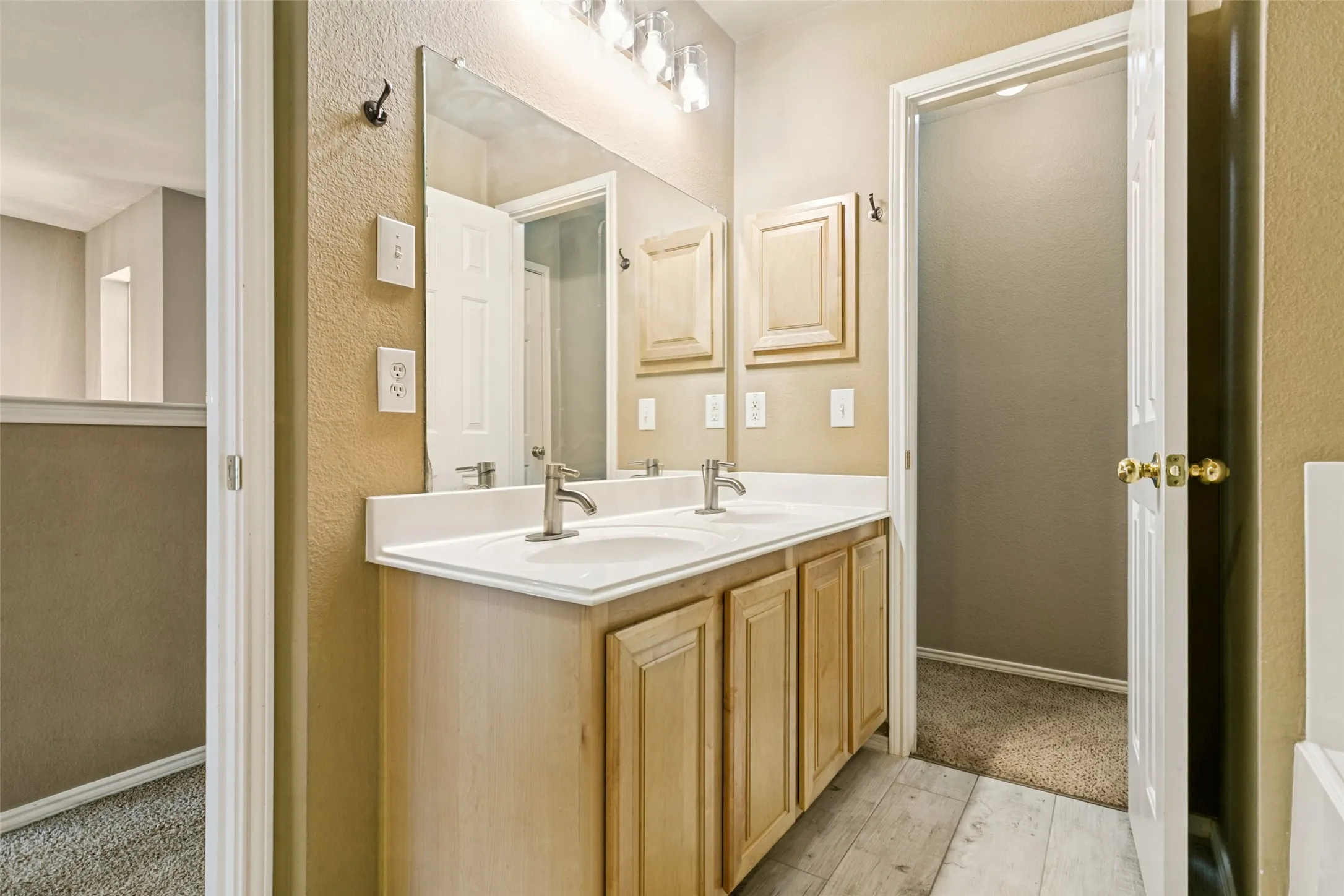 Double vanity with brushed nickel faucets, wood-finish cabinetry, and overhead lighting