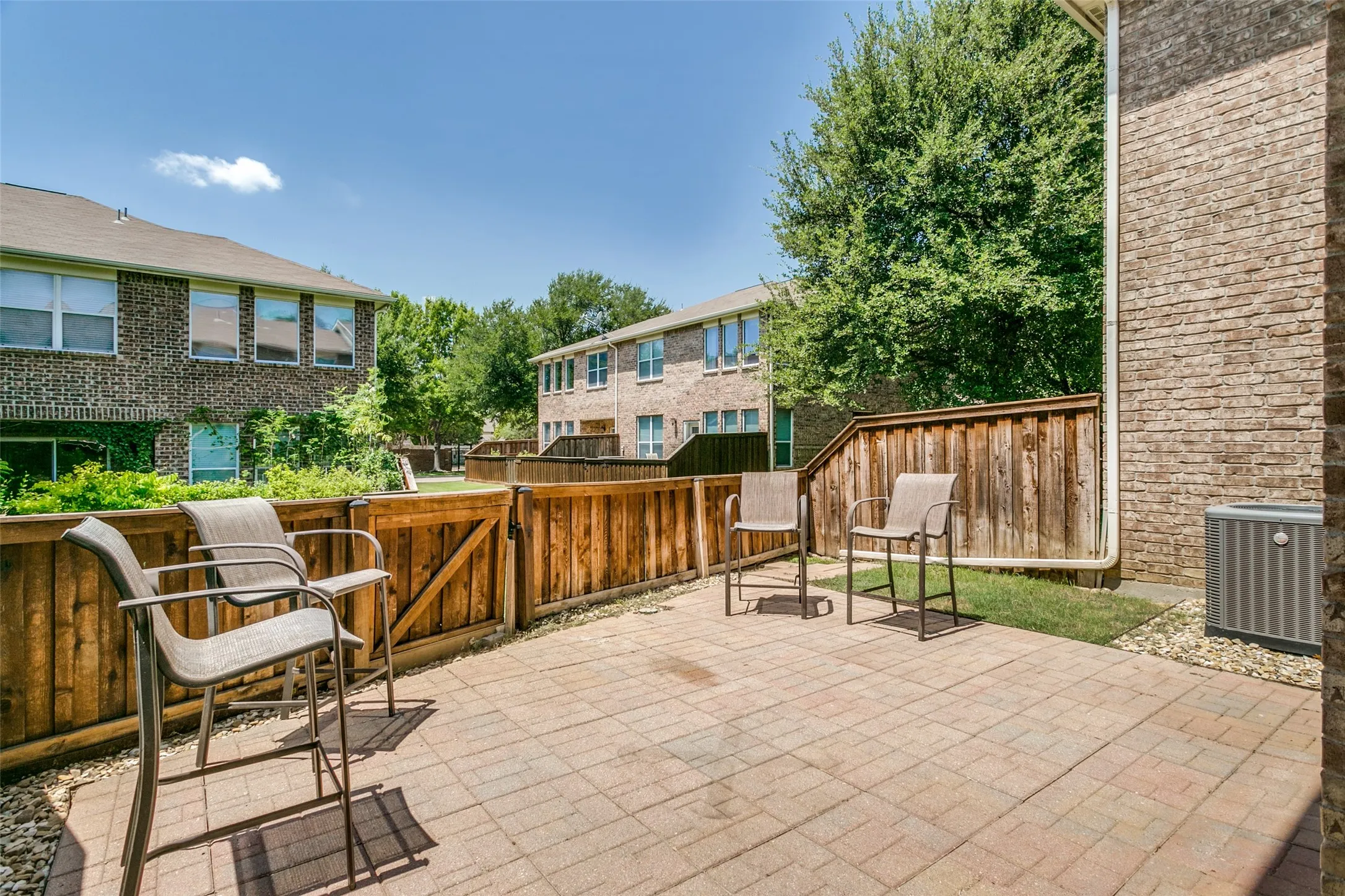 Brick paver patio with a wood privacy fence and a security gate