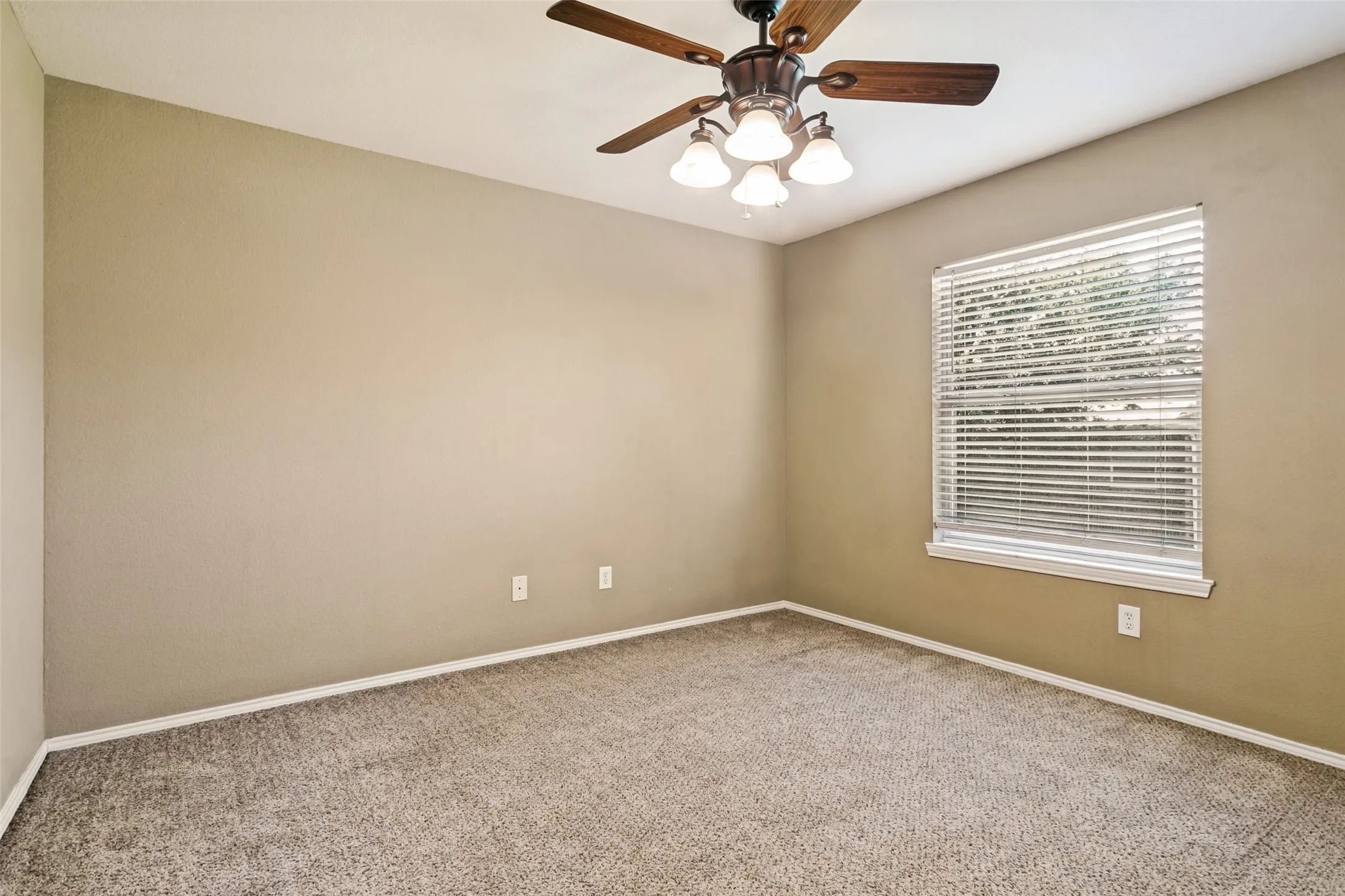 Neutral tone walls and featuring a single window with blinds and a ceiling fan with integrated lighting