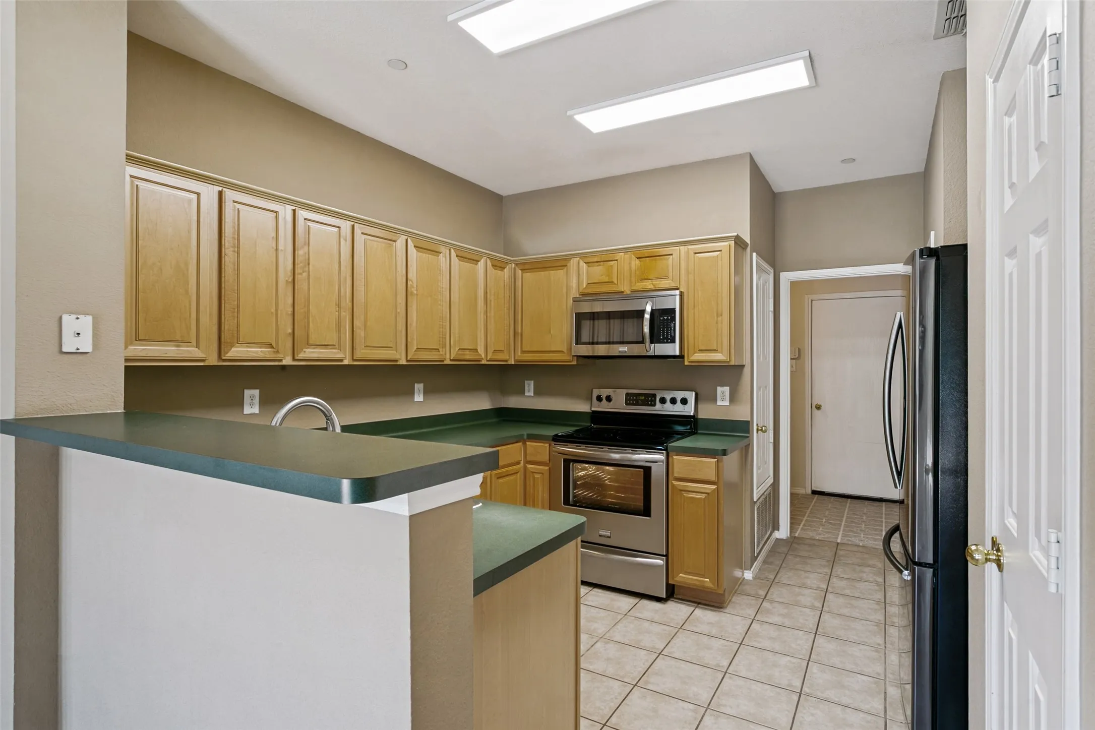 Kitchen featuring wood cabinetry, stainless steel appliances, a breakfast bar, and tile flooring