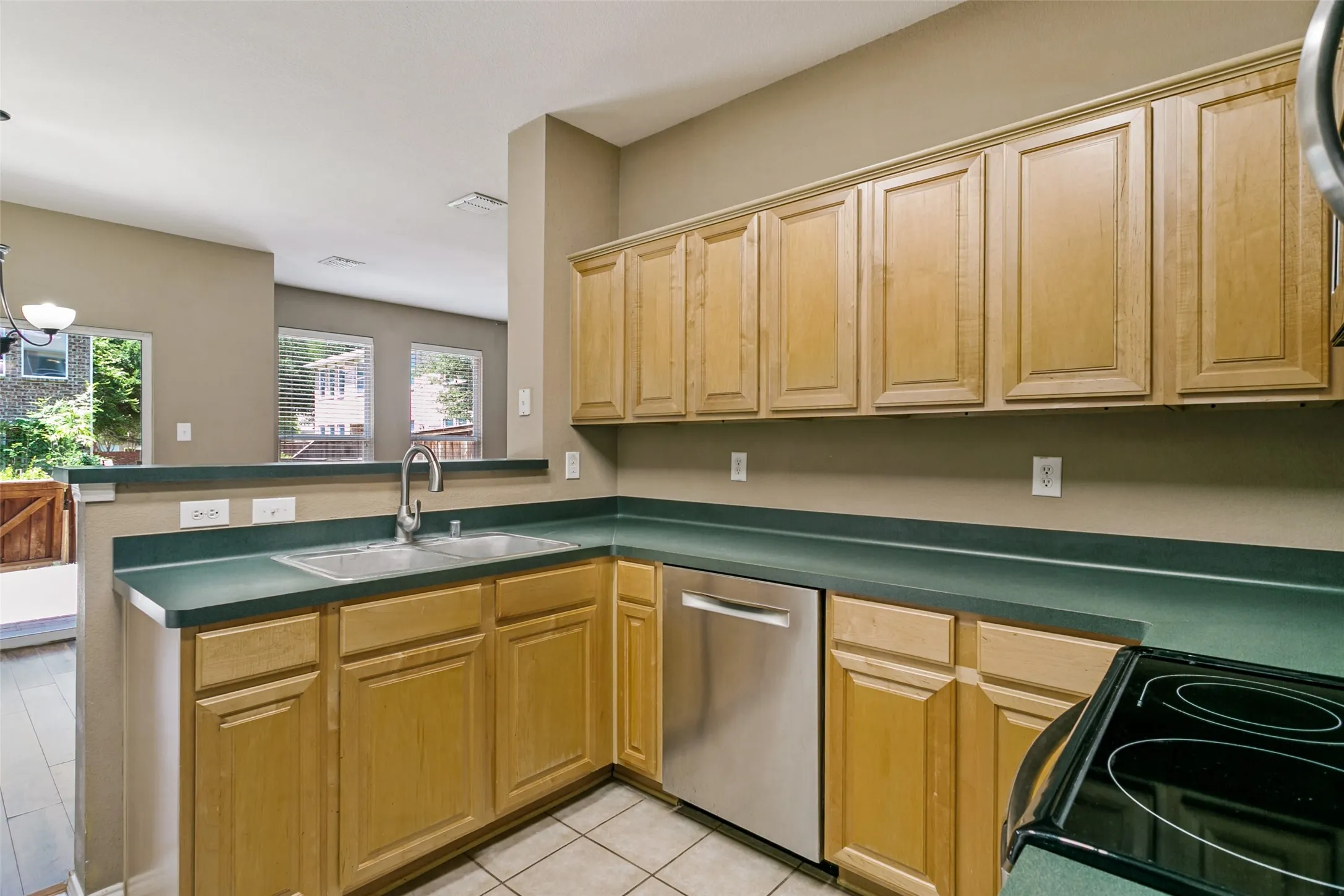 Kitchen featuring ample wood cabinetry, a stainless steel dishwasher, a double basin sink, black electric range, and Samsung refrigerator included.