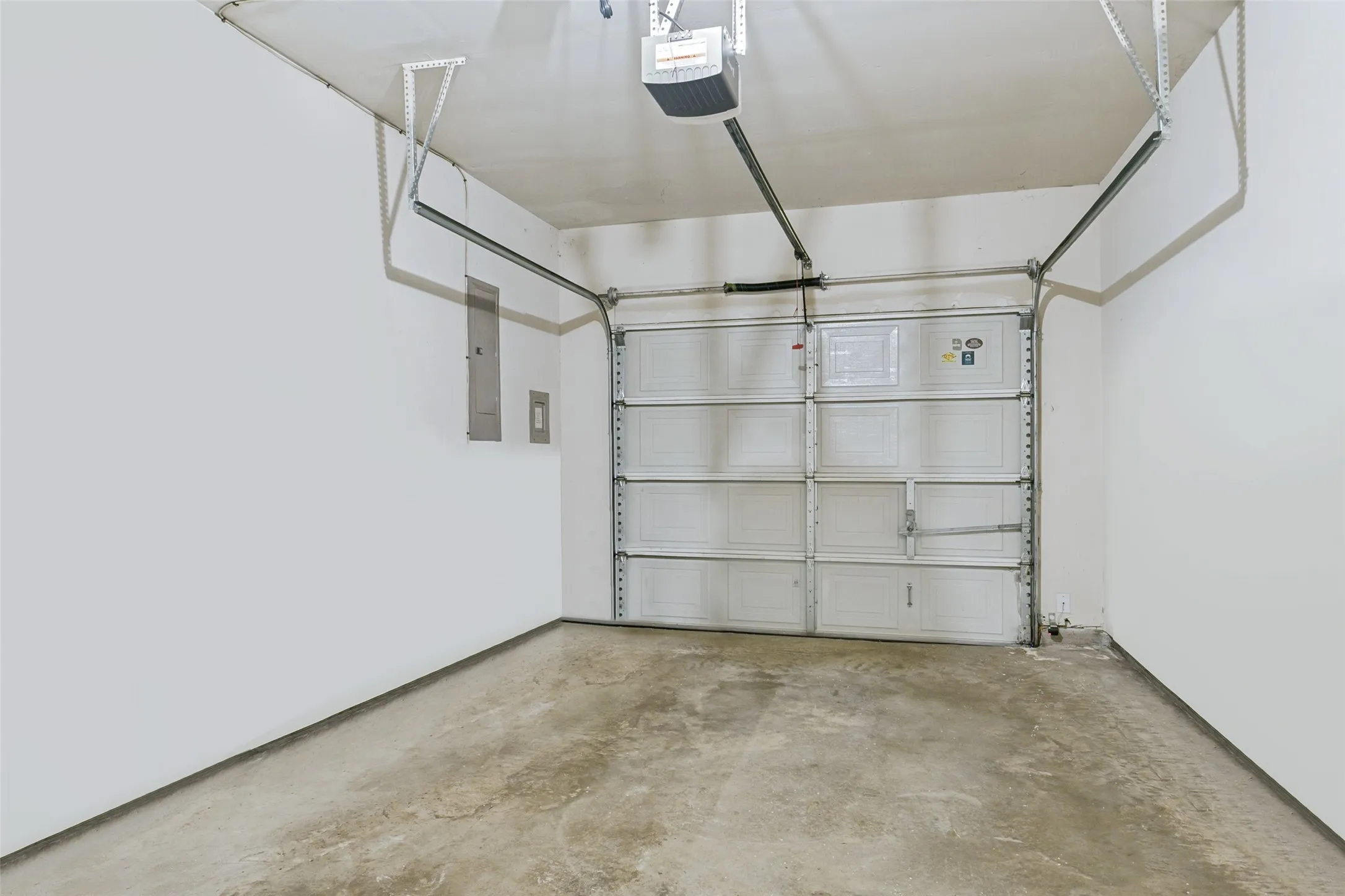 Attached garage featuring a sectional door, concrete flooring, and an overhead door opener