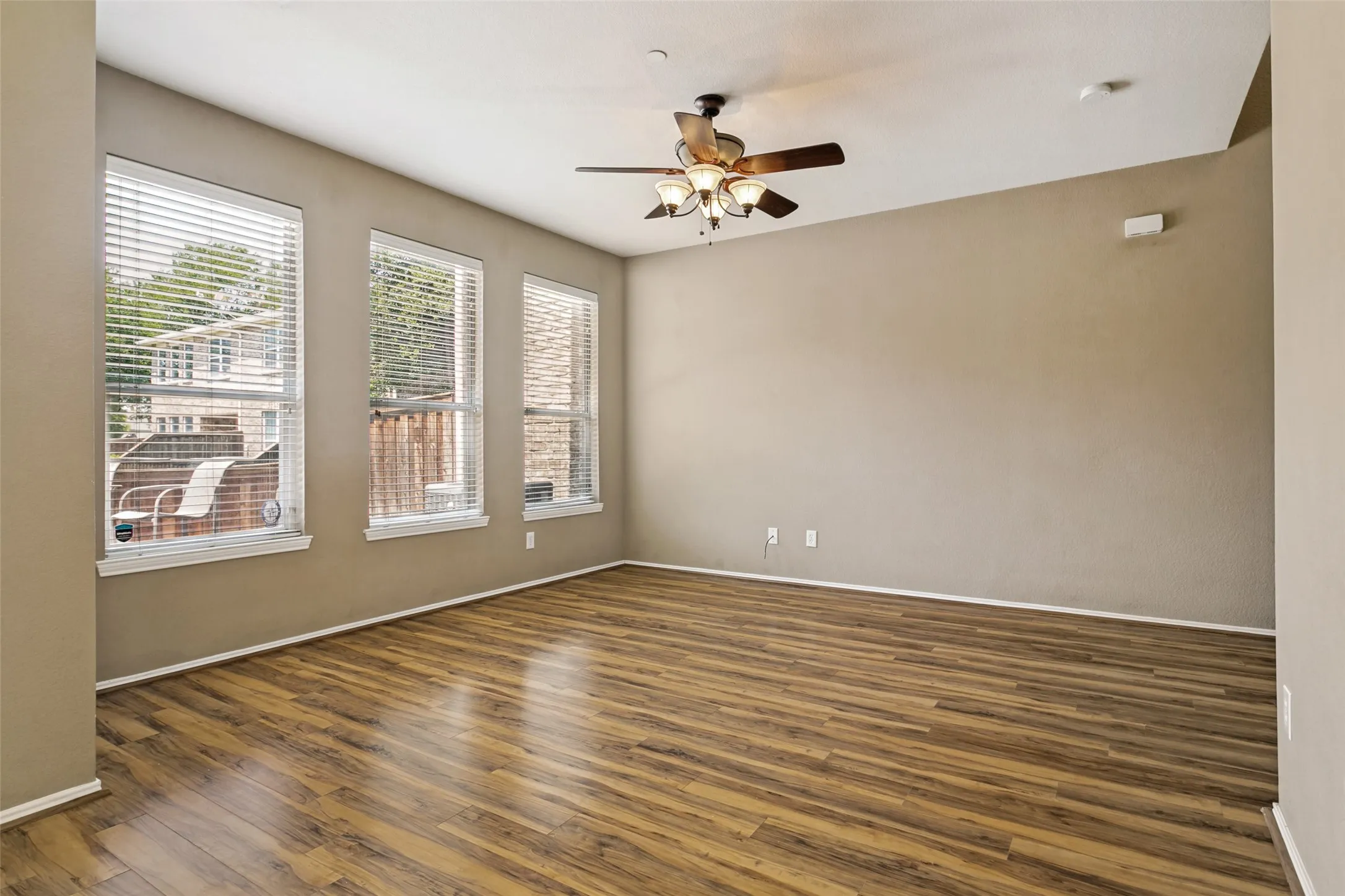 Pergo flooring, multiple windows with blinds, and an overhead ceiling fan