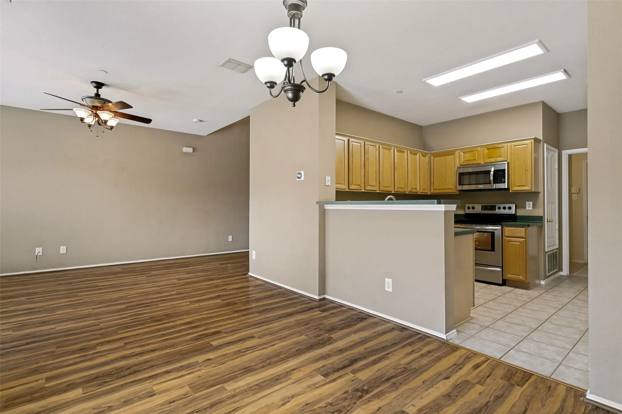 Pergo flooring throughout, ceiling fan, kitchen with wood cabinetry, stainless steel appliances, and tile flooring
