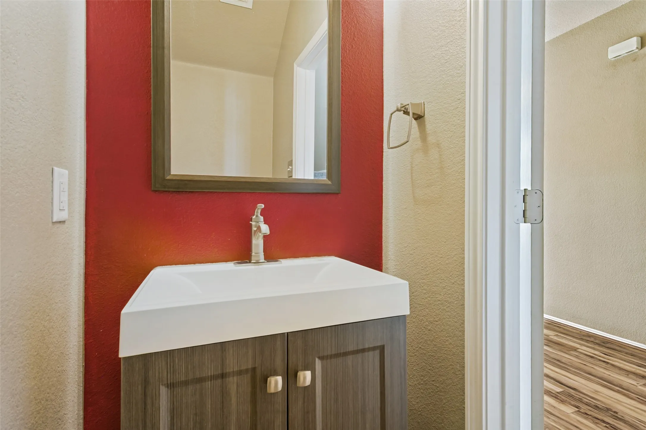 Vanity with integrated sink, wood-finish cabinetry, and brushed nickel faucet