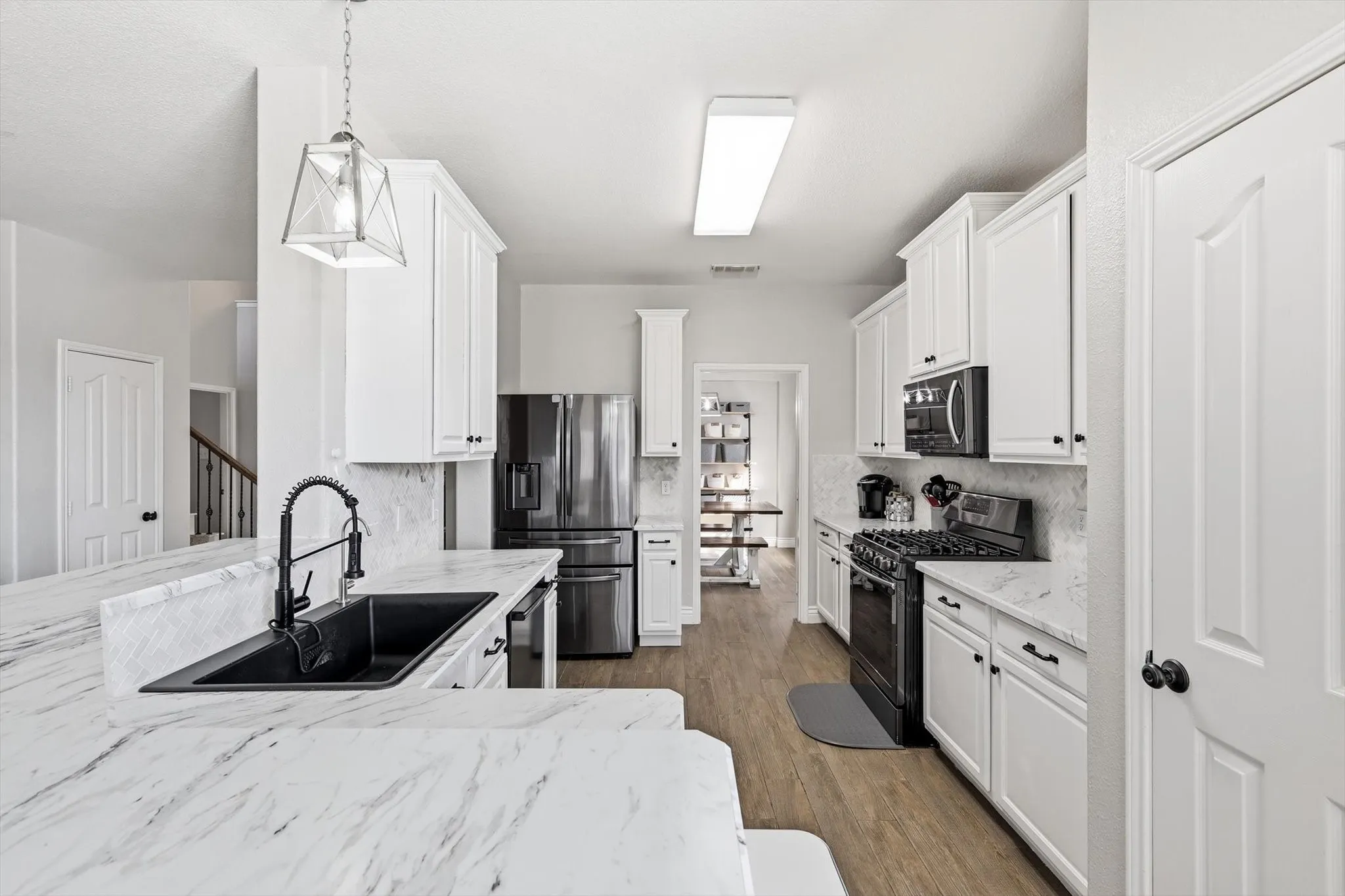 Modern kitchen featuring white cabinetry, stone-finish countertops, and wood-finish flooring