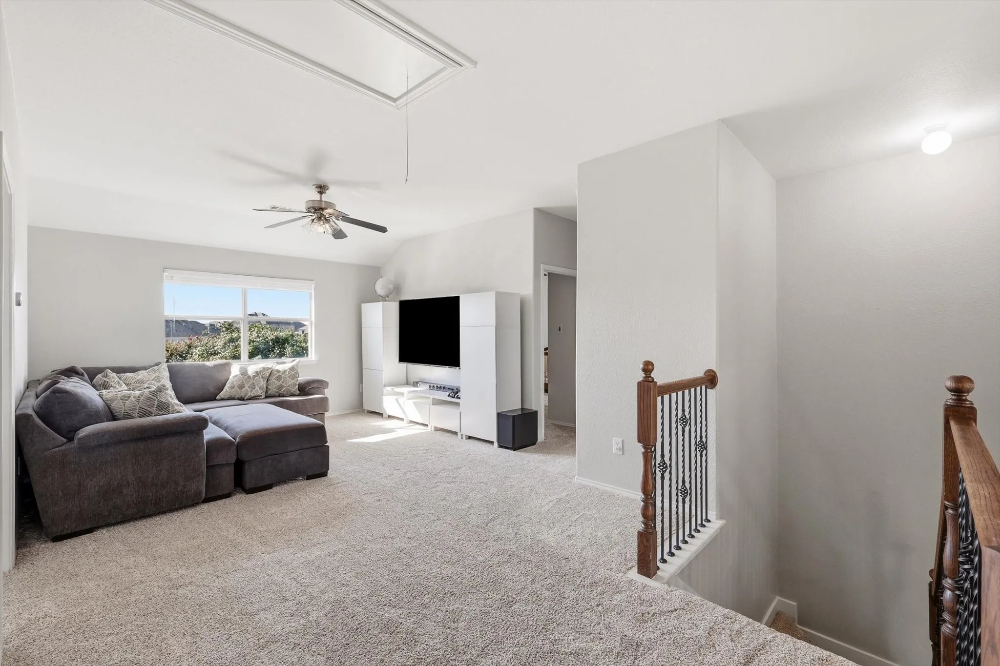 Spacious carpeted bonus room featuring a sloped ceiling, attic access, and a window providing natural light