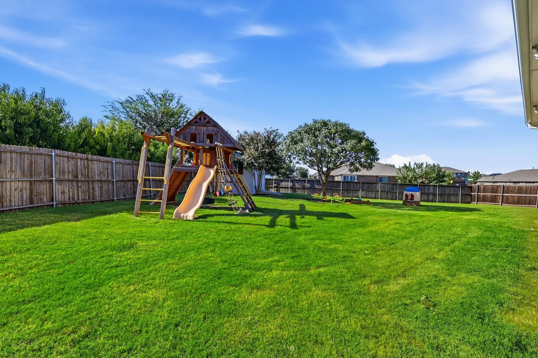 Expansive backyard featuring a lush lawn, a full wood privacy fence, and mature trees