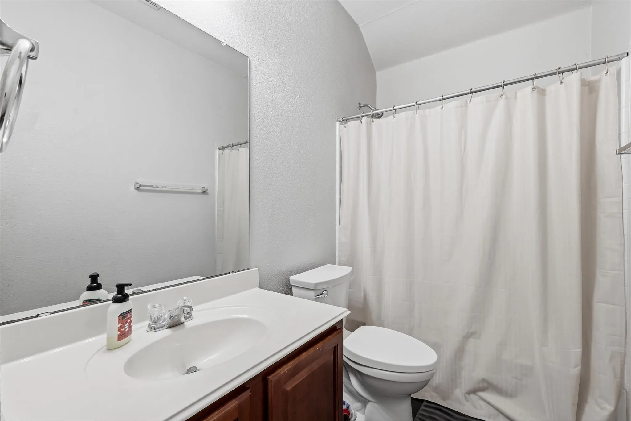 Bathroom featuring a wood-finish vanity with an integrated white sink and chrome faucet