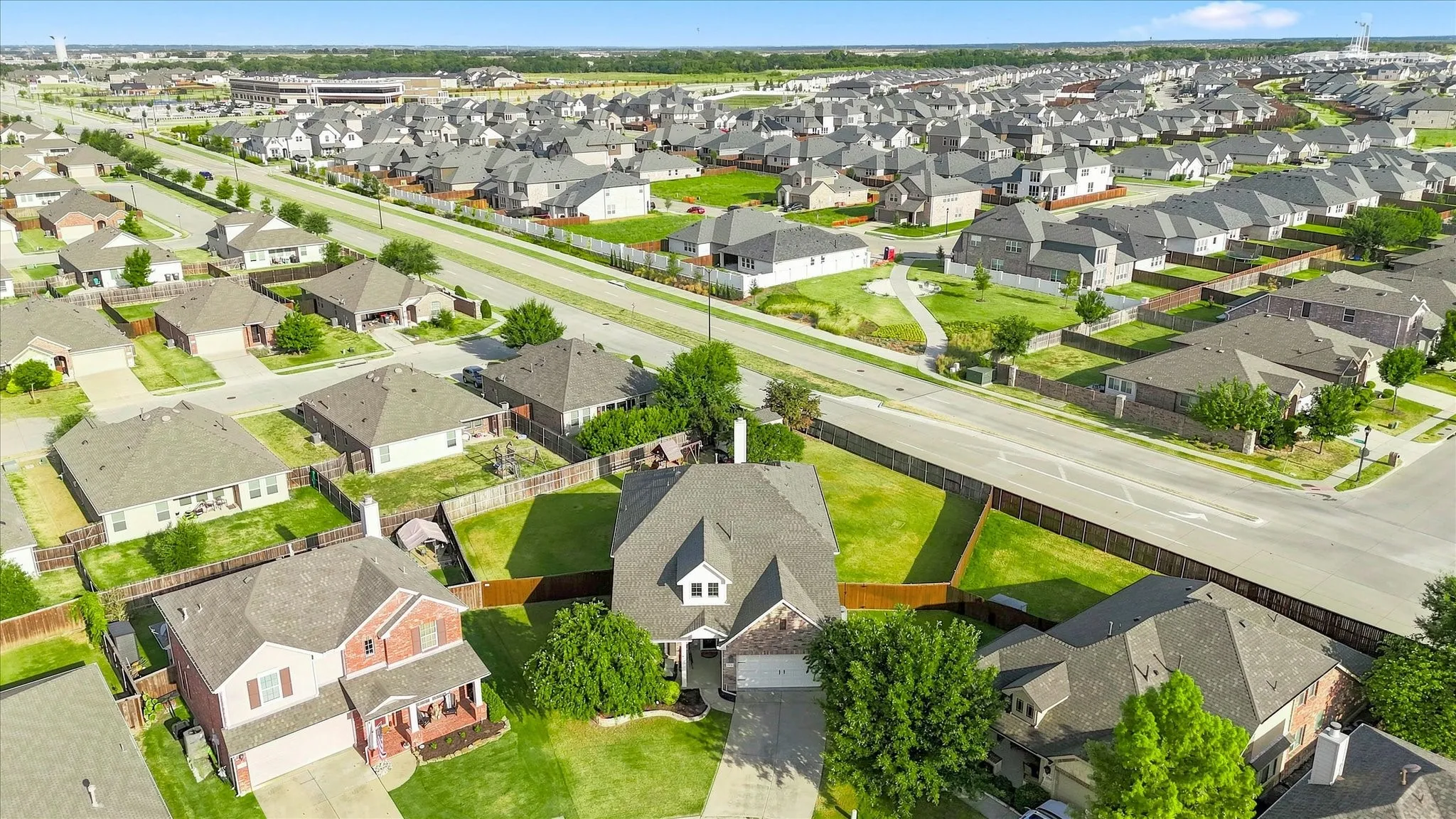 Aerial perspective showcasing a residential neighborhood with uniformly designed homes, tree-lined streets, and expansive green spaces
