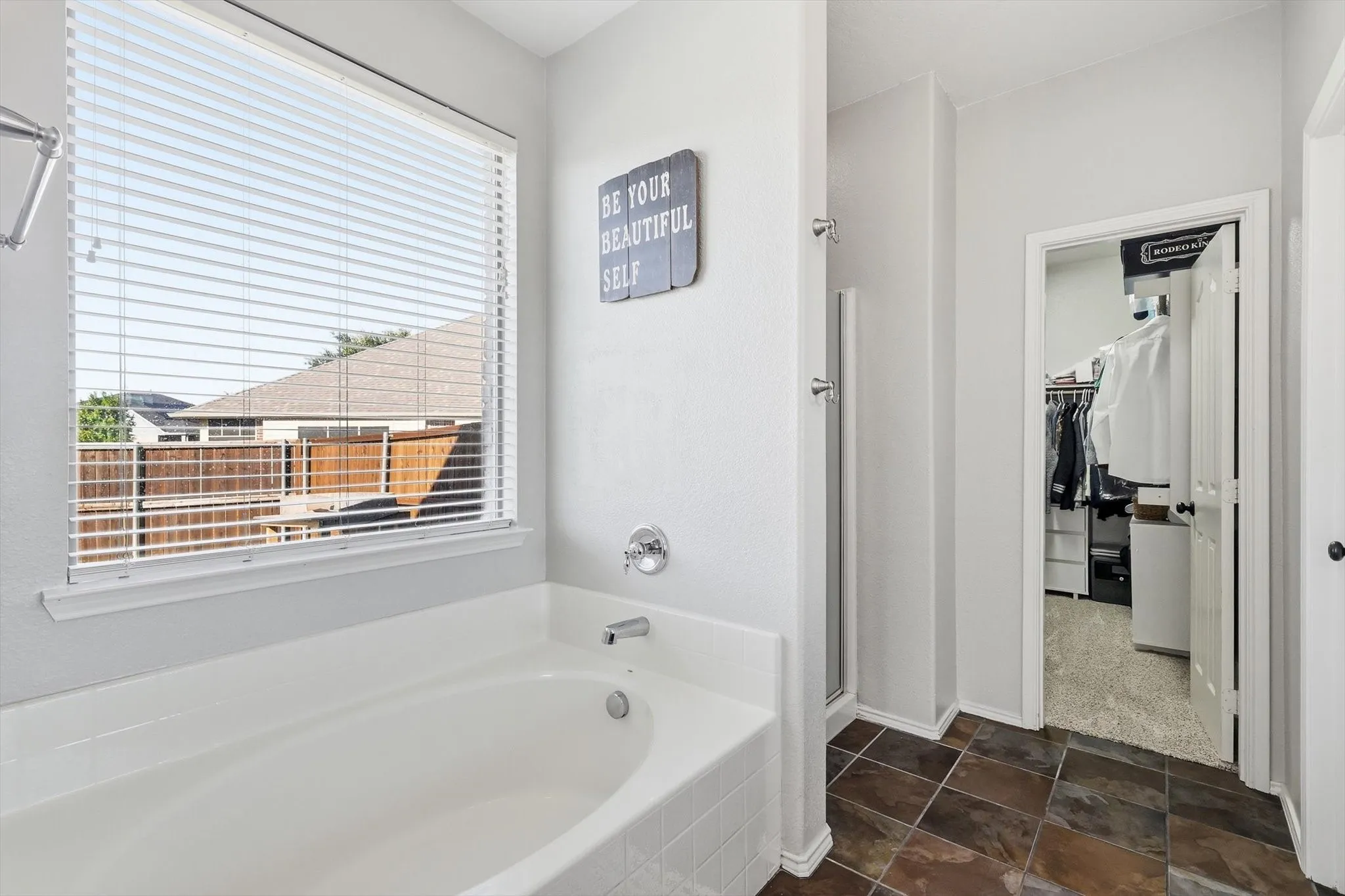 Soaking tub featuring a chrome faucet and window with blinds