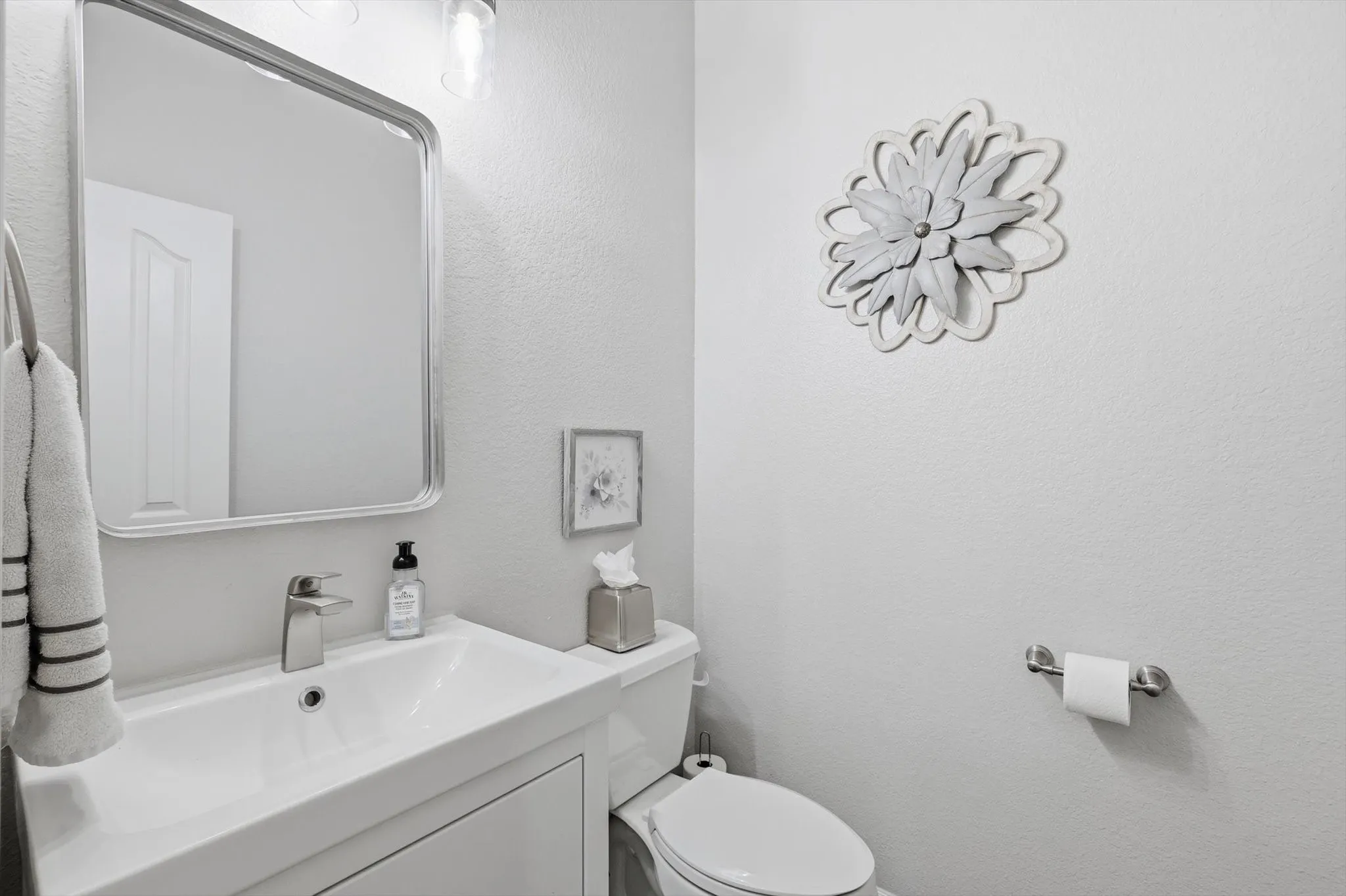 White vanity with integrated sink, brushed nickel faucet, and framed mirror