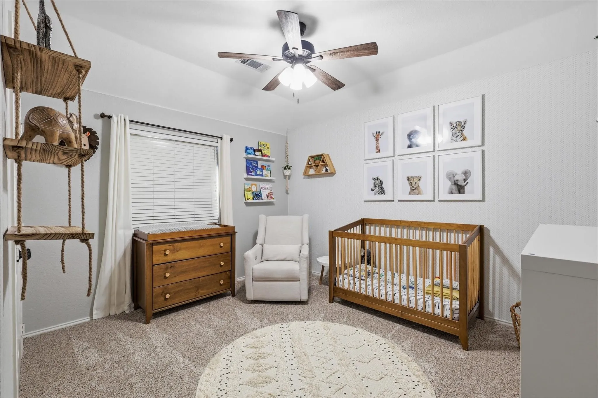 Carpeted room featuring a ceiling fan with light, a window with blinds and curtains, and built-in shelving