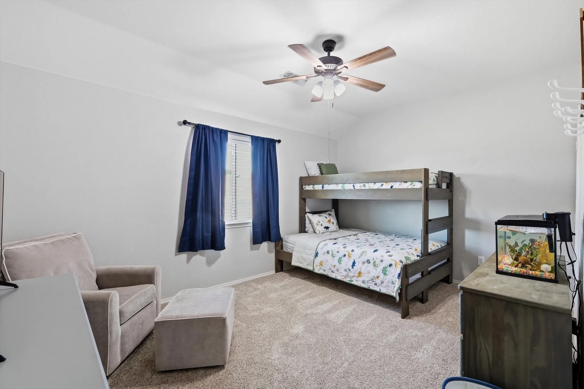 Carpeted room featuring a ceiling fan with light fixture, window with blinds and dark blue drapes, and light gray walls