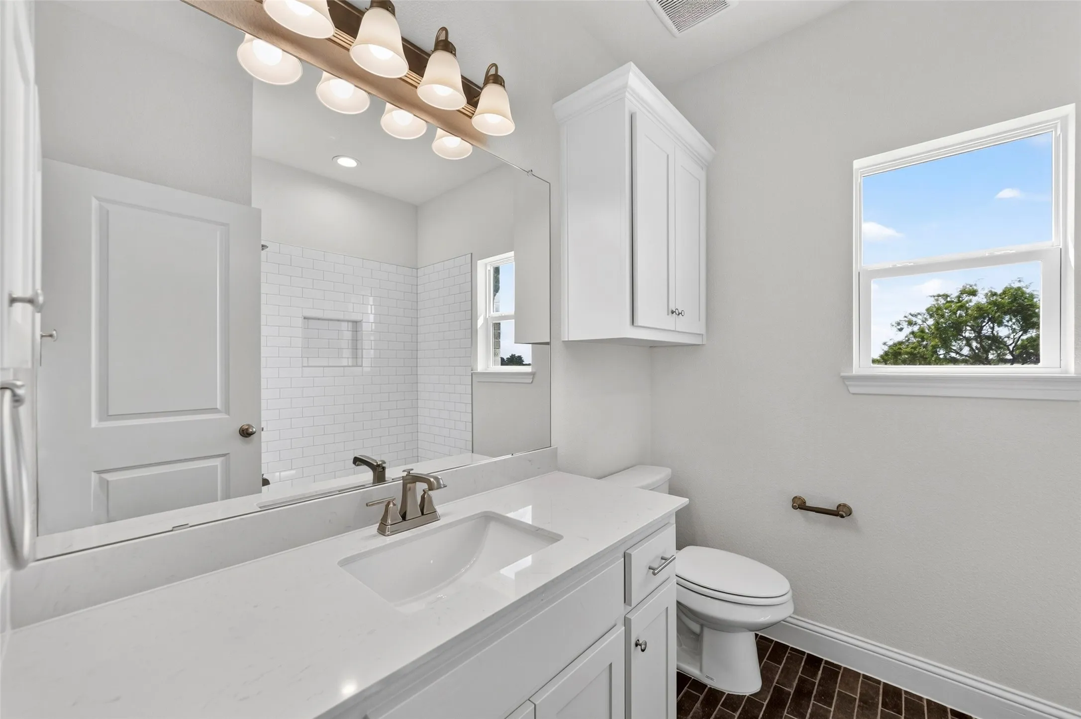 Bathroom featuring a white vanity with an integrated sink, brushed nickel faucet, and a large mirror