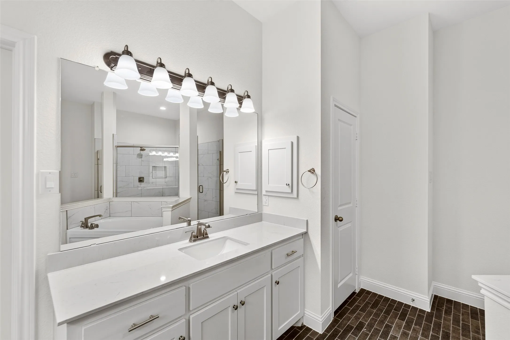 Bathroom vanity featuring a quartz countertop, integrated sink, and white cabinetry with brushed nickel hardware